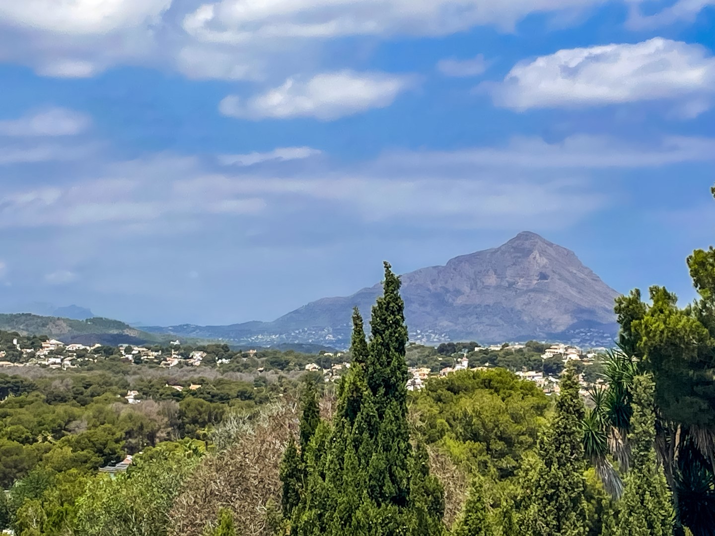 Panoramablick vom Grundstück über das Tal und den Berg Montgó, umgeben von üppigem mediterranem Grün unter klarem Himmel.