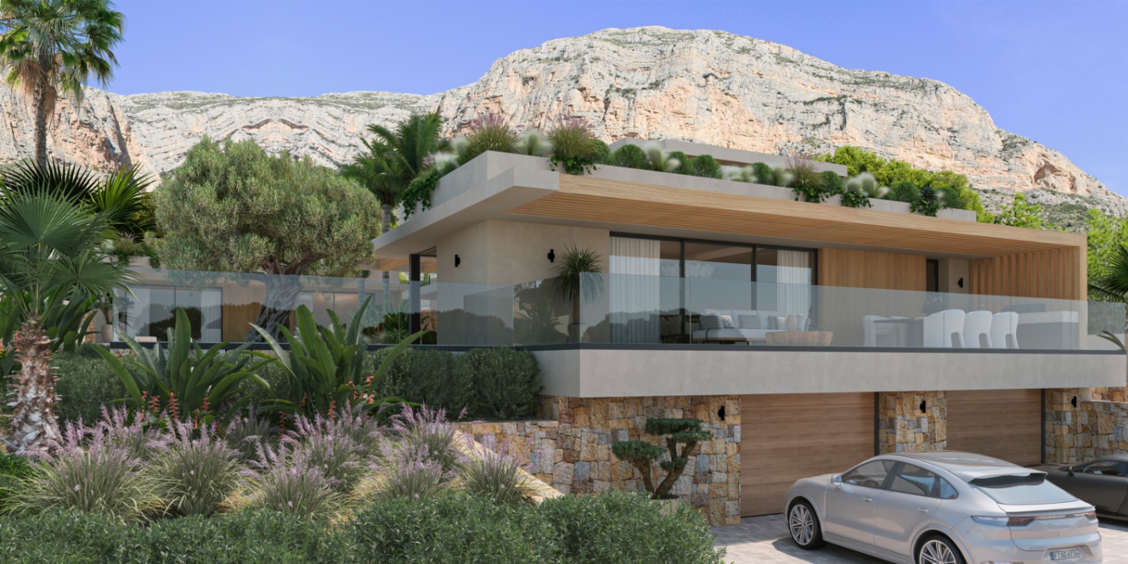 Moderne Villa mit Natursteinwänden, großen Glasfronten und einer Terrasse mit Glasgeländer vor der markanten Kulisse des Montgó-Massivs in Jávea.