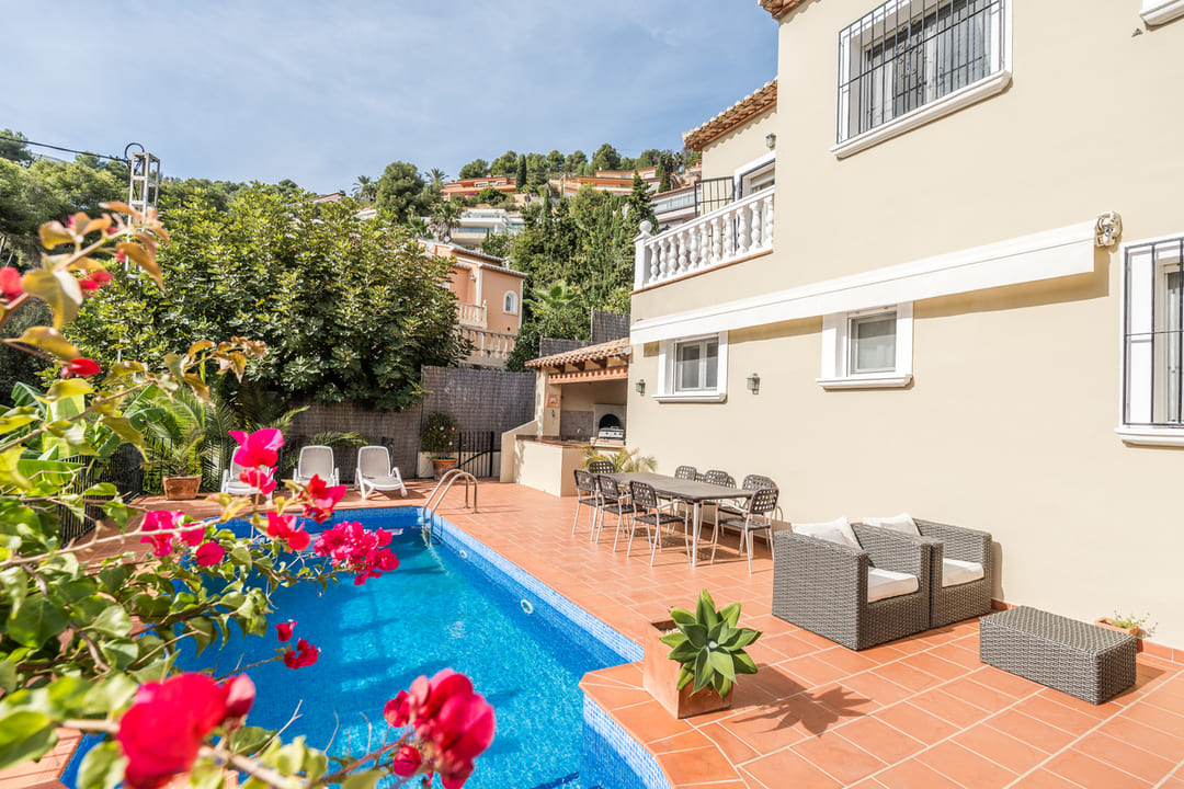 Terrasse mit privatem Pool, Terrakottaboden und Essbereich im Freien. Ausgestattet mit gemauertem Grill und Loungemöbeln vor einer cremefarbenen Fassade.