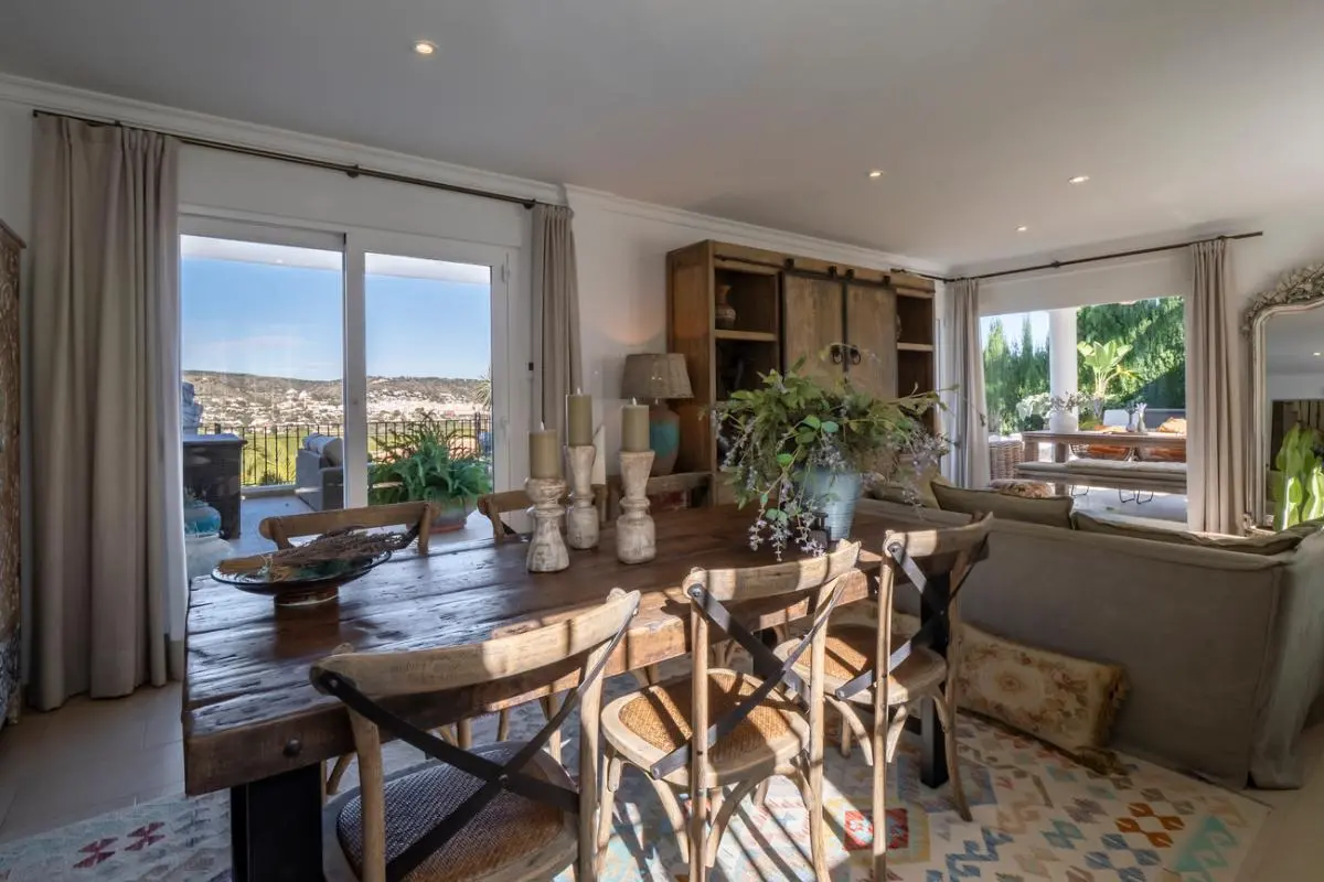 Rustikaler Essbereich mit Massivholztisch und Crossback-Stühlen, der durch Glasschiebetüren auf eine Terrasse mit Talblick führt.