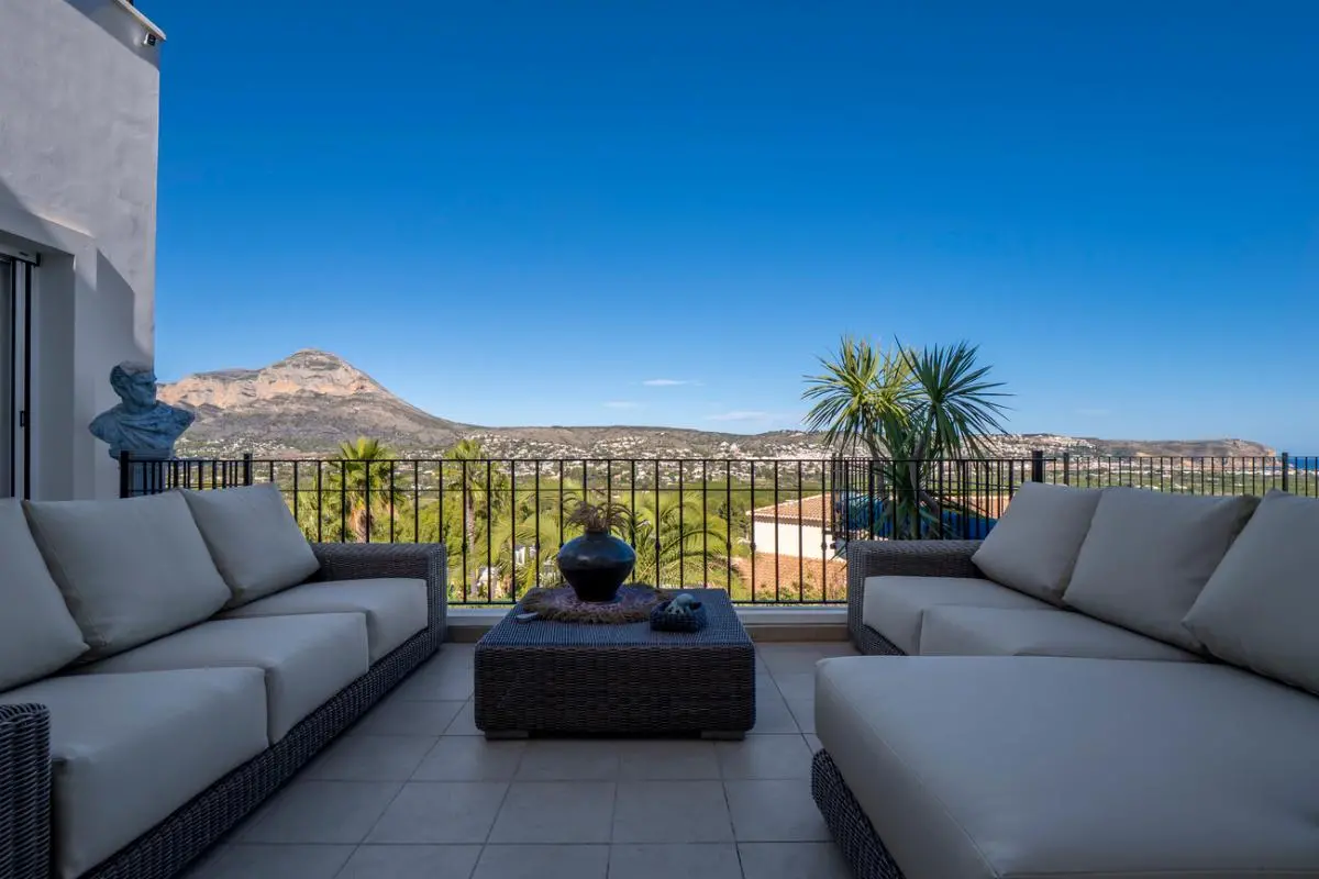 Terrassenlounge mit grauen Rattansitzmöbeln und Panoramablick auf den Berg Montgó und das weite Tal.