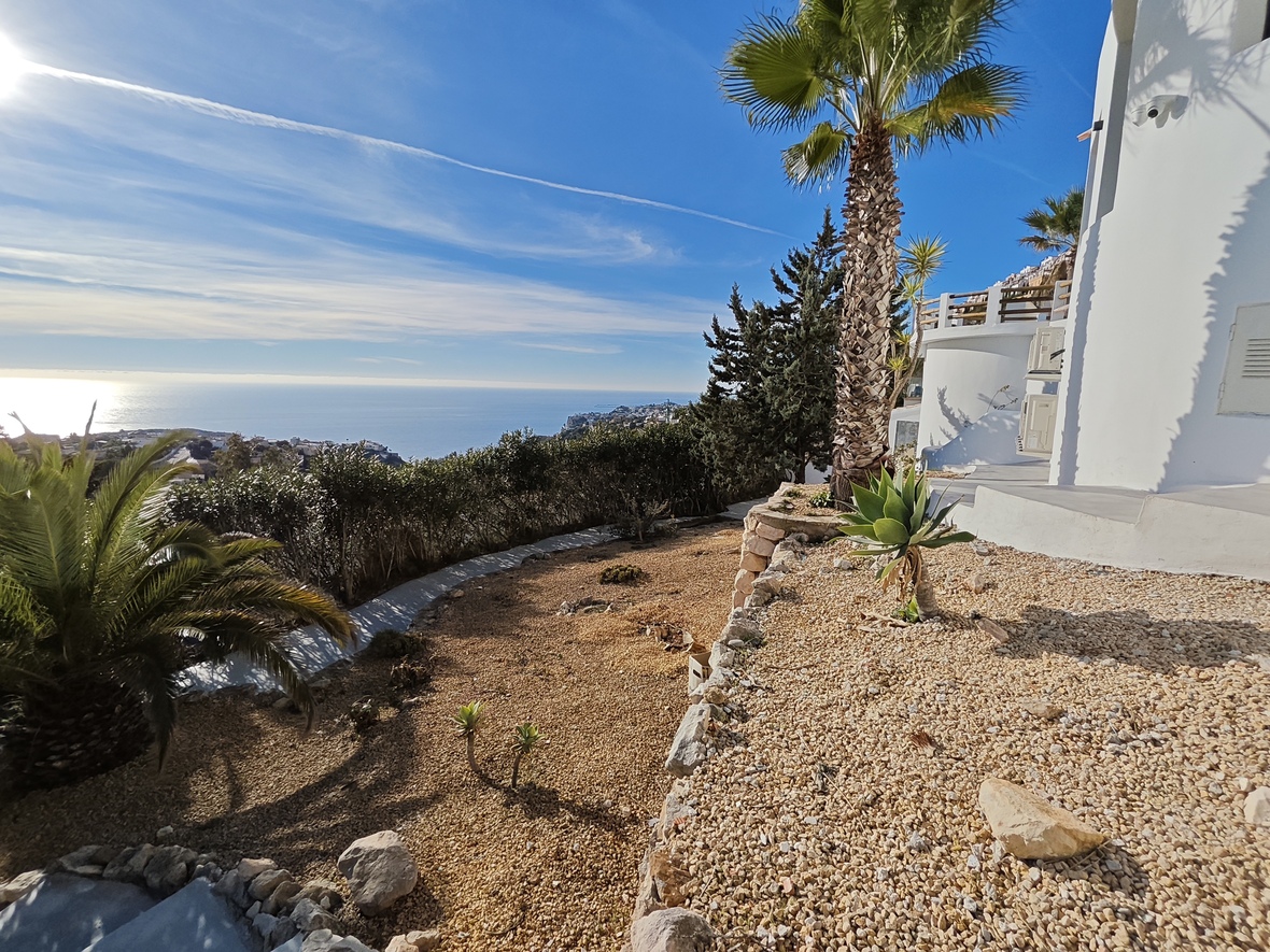 Erhöhte Gartenterrasse mit Kieslandschaft, Palmen und Sukkulenten, die einen weiten Panoramablick auf das Mittelmeer und die Küste bietet.
