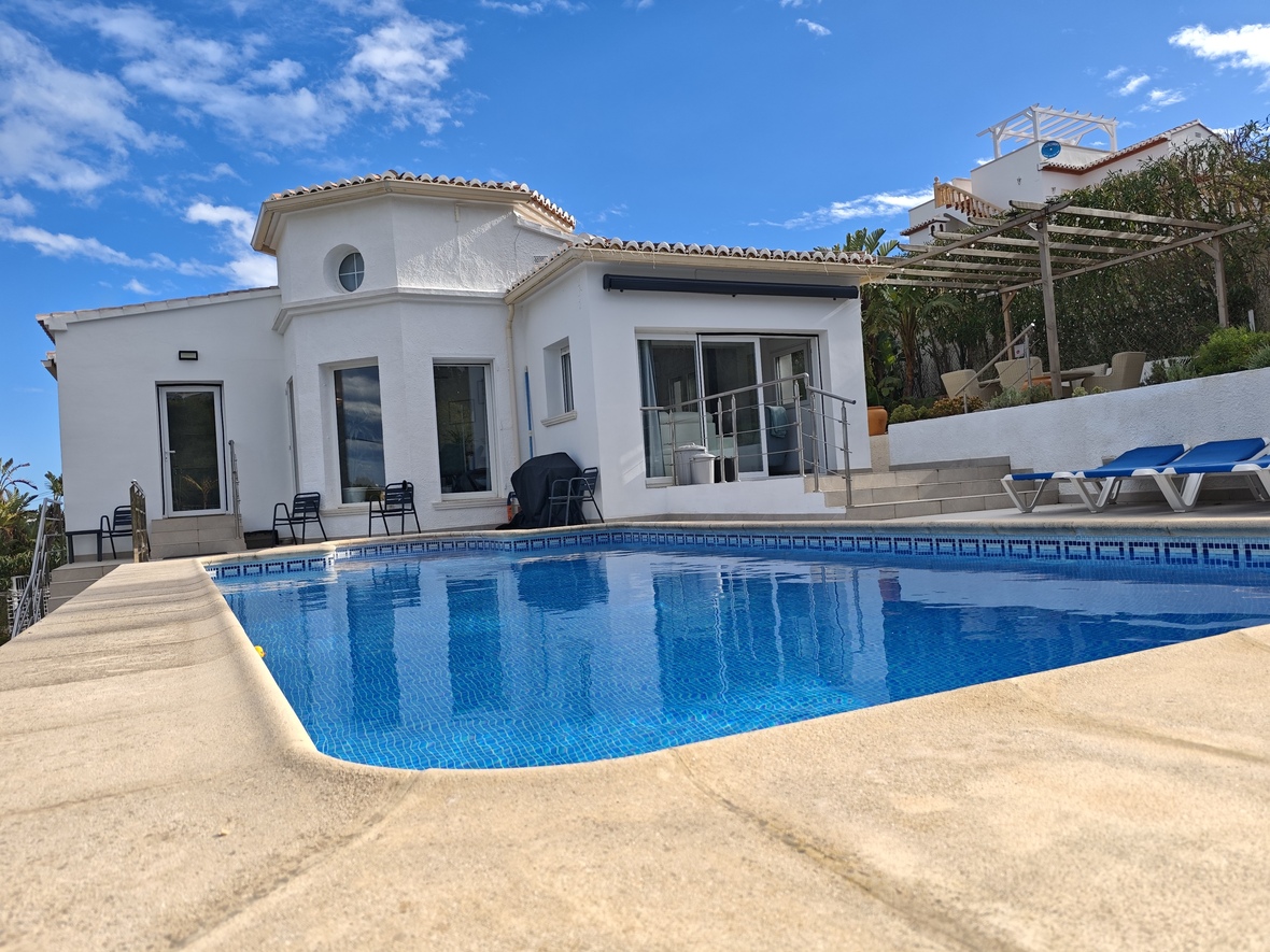 Privater Swimmingpool mit blauen Mosaikfliesen, umgeben von einer Steinterrasse und einer weißen Villa mit einem markanten Rundturm-Element.