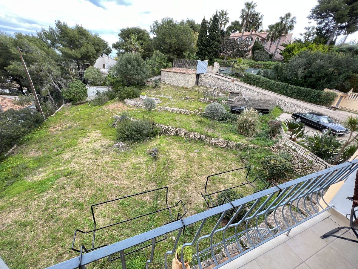 Erhöhter Blick von der Terrasse auf das terrassierte Gartengrundstück mit Natursteinmauern und typisch mediterranem Baumbestand.