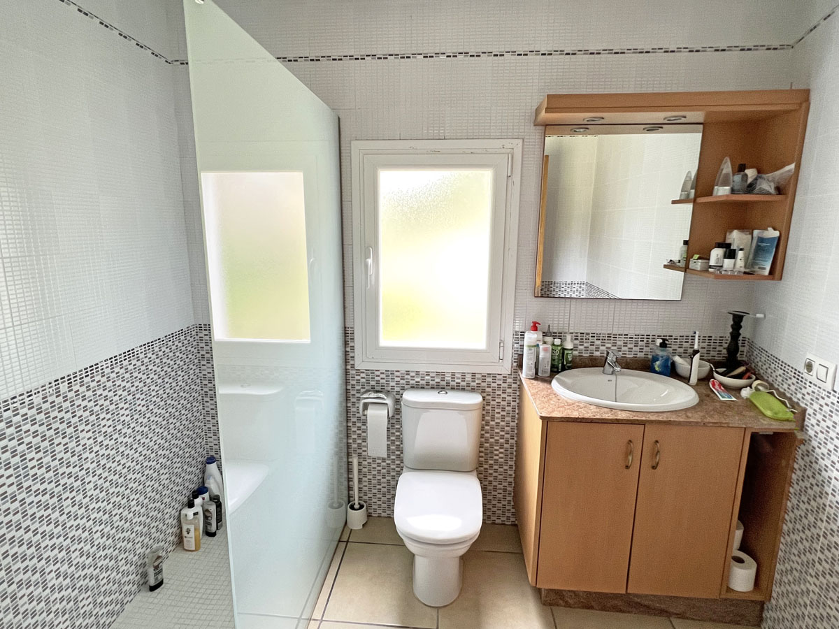 Funktionales Badezimmer mit begehbarer Dusche, Milchglastrennwand, Holz-Waschtisch mit Marmor-Arbeitsplatte und dekorativen Mosaikfliesen.