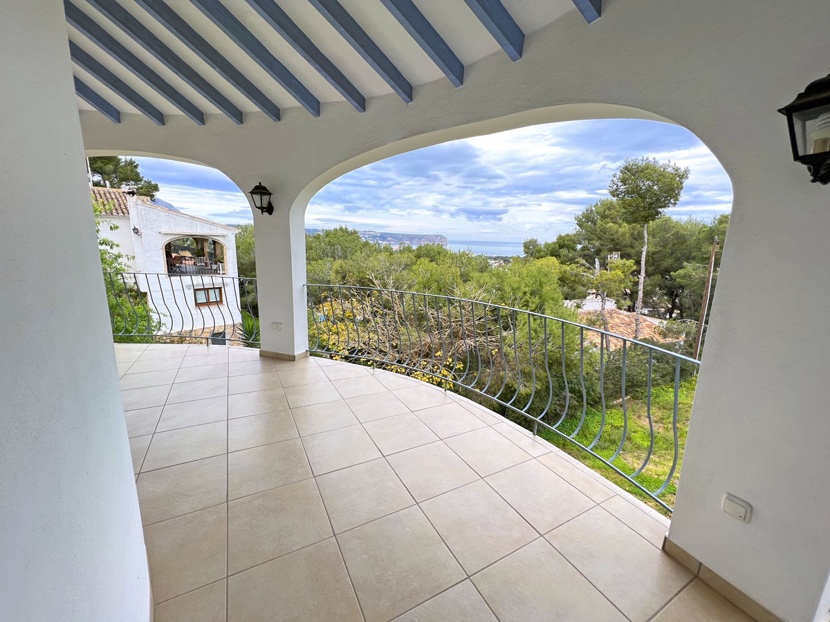 Überdachte Terrasse mit hellblau gestrichenen Holzbalken, Fliesenboden und geschwungenem Metallgeländer mit Blick auf das Meer und das Cabo San Antonio.