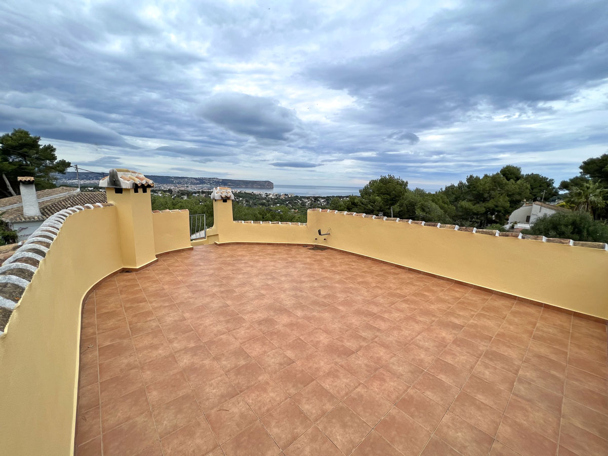 Weitläufige Dachterrasse mit Terrakotta-Fliesen und geschwungener Brüstung, die einen Panoramablick auf das Meer und das Cabo San Antonio bietet.