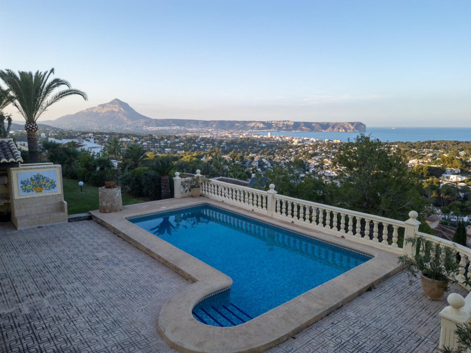 8x4 m großer Pool mit Panoramablick auf die Bucht von Jávea und den Montgó, eingebettet in eine geflieste Terrasse mit klassischer weißer Balustrade.