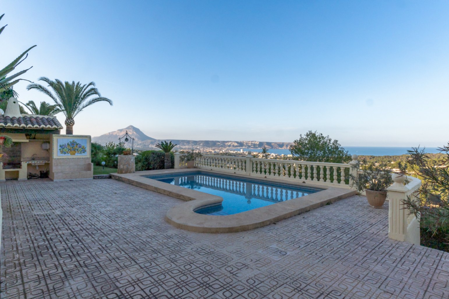 Außenpool mit römischer Treppe und gefliester Terrasse, umgeben von einer klassischen Balustrade mit Panoramablick auf die Bucht von Jávea und den Montgó.