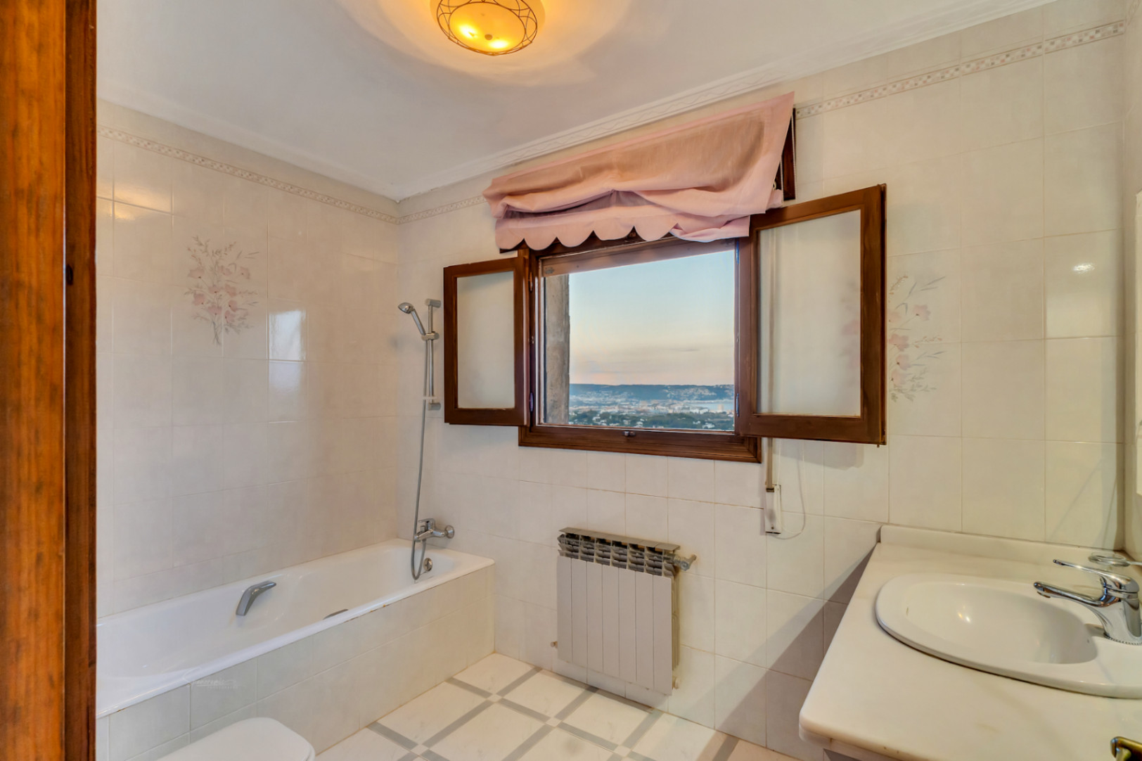 Badezimmer mit Badewanne, Marmor-Waschtisch und einem Holzfenster mit Panoramablick auf die Bucht von Jávea und die Küste.