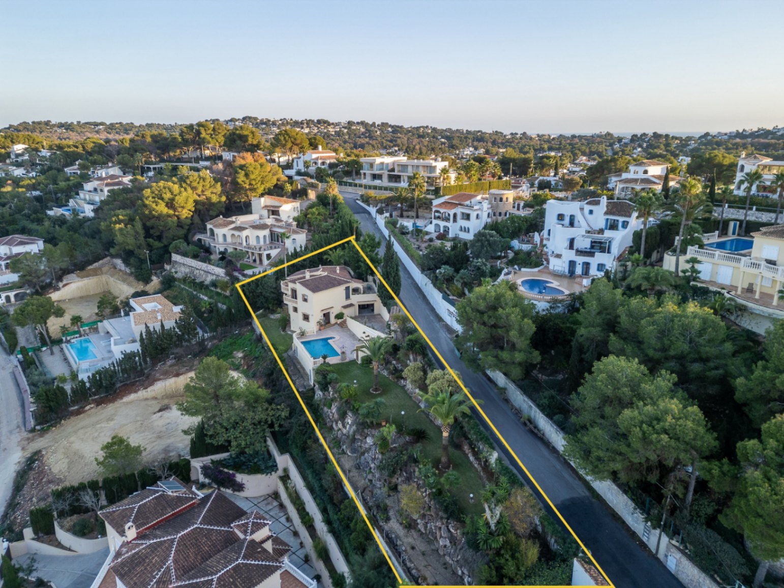 Luftaufnahme des abgegrenzten Grundstücks mit der mediterranen Villa, dem privaten Pool und dem terrassierten Garten mit Palmen in Costa Nova.