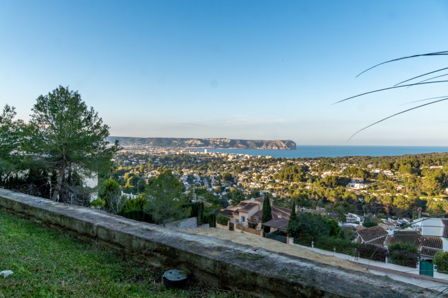 Panoramablick vom Grundstück über die Bucht von Jávea und das Cabo San Antonio, der die mediterrane Küstenlandschaft und die umliegende Natur zeigt.