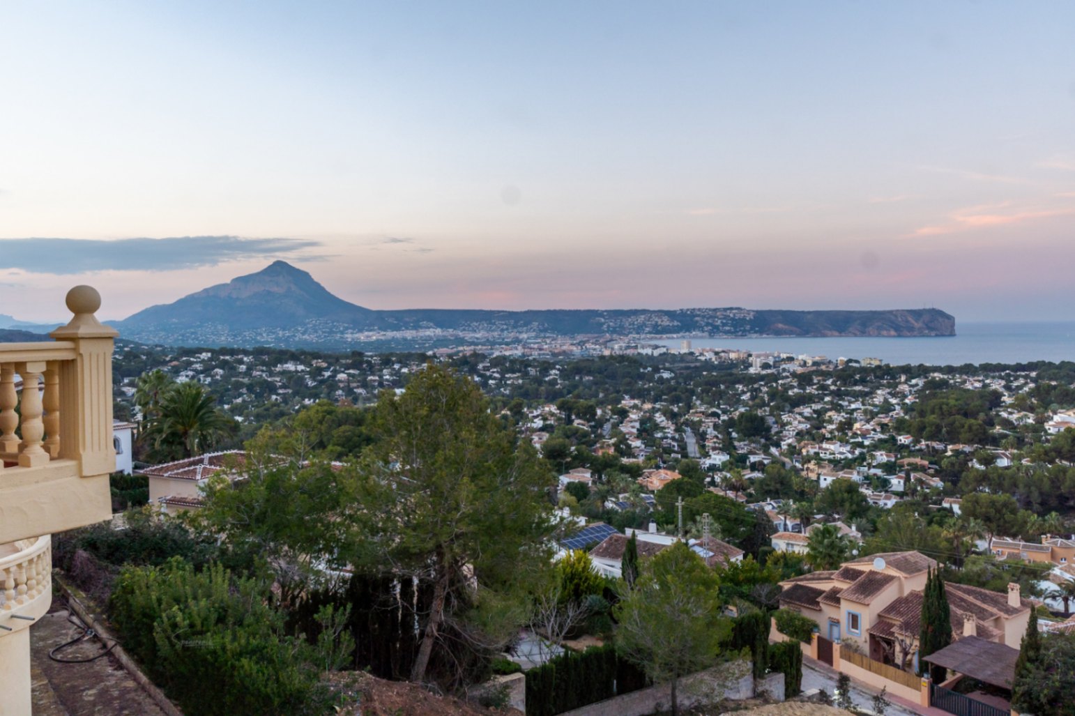 Panoramablick von der Terrasse auf die Bucht von Jávea, den Berg Montgó und das Cabo San Antonio in der Abenddämmerung, umgeben von Pinien.