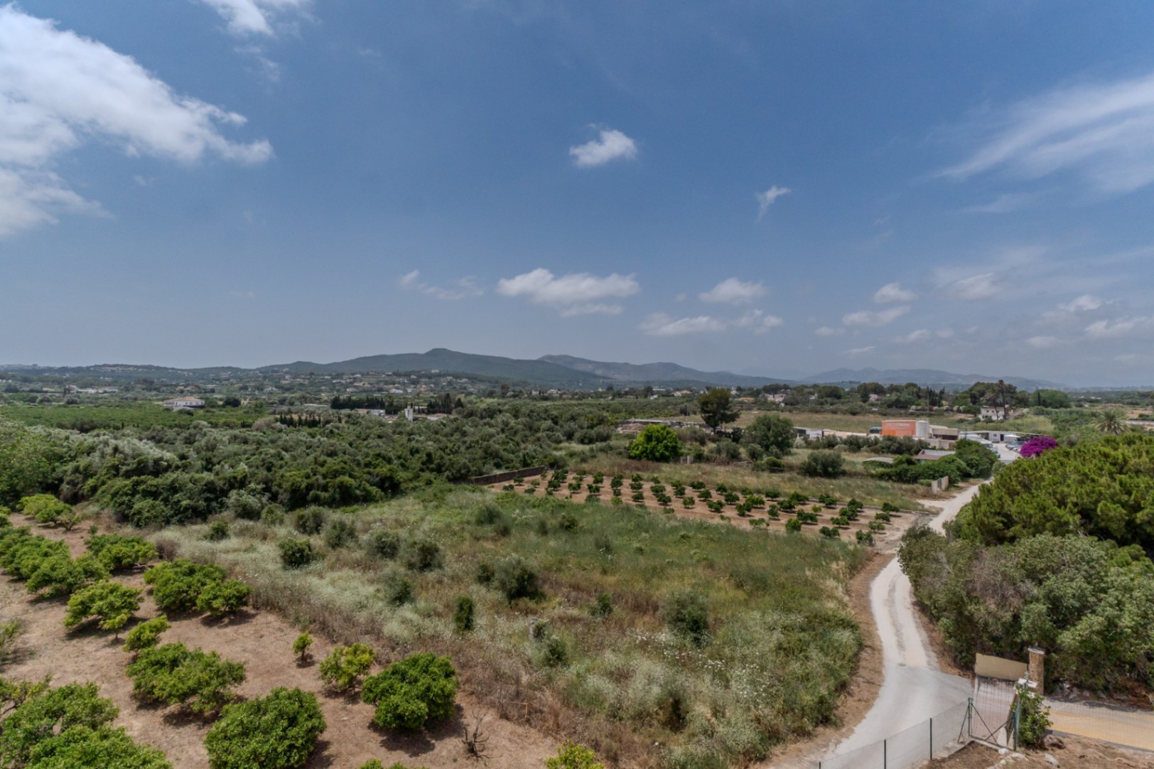 Erhöhter 180-Grad-Panoramablick über das Tal von Jávea mit Blick auf landwirtschaftliche Obsthaine und die Bergkette von Benitachell.