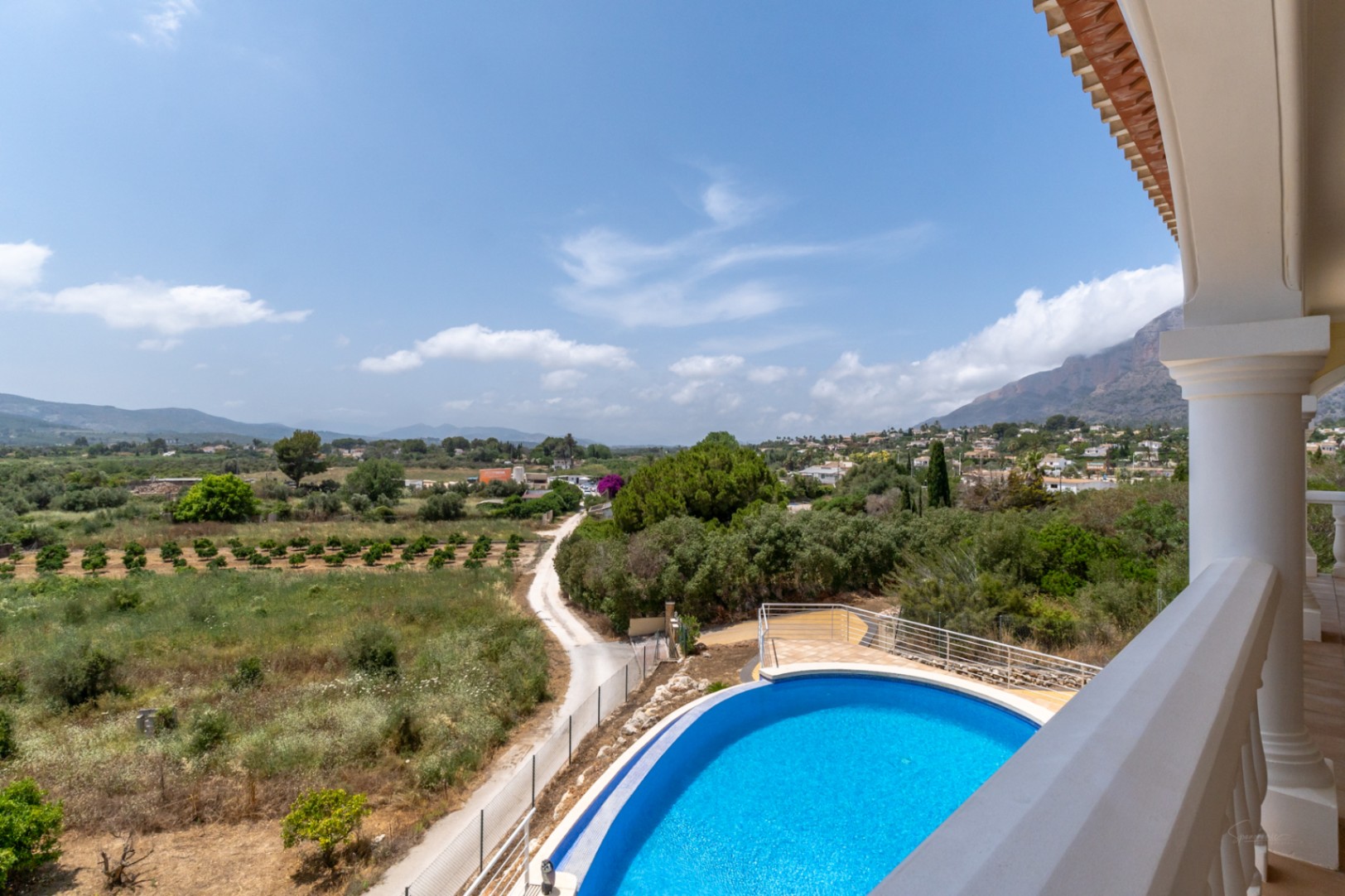 Erhöhter Blick von der Terrasse auf den ovalen Pool und das 180-Grad-Panorama über das Tal bis hin zum Berg Montgó.