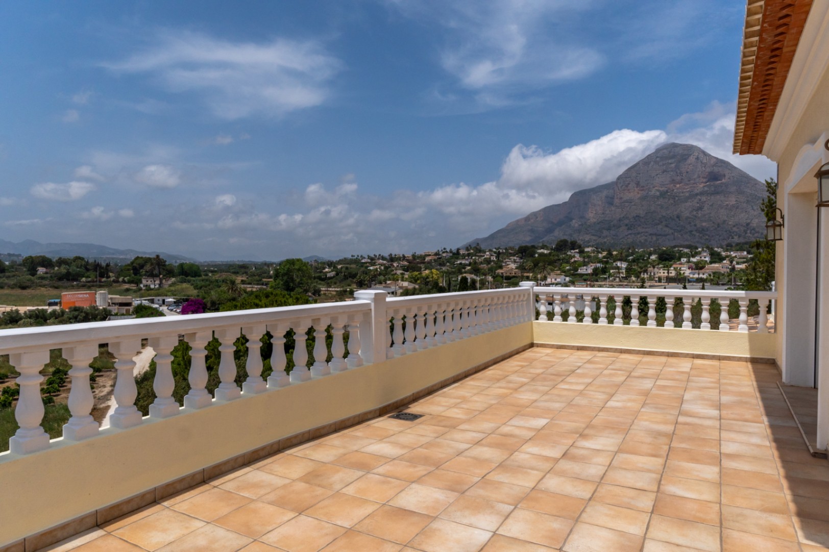 Obere Terrasse mit terrakottafarbenen Fliesen und weißer Balustrade, die einen Panoramablick auf den Berg Montgó und das Tal von Jávea bietet.