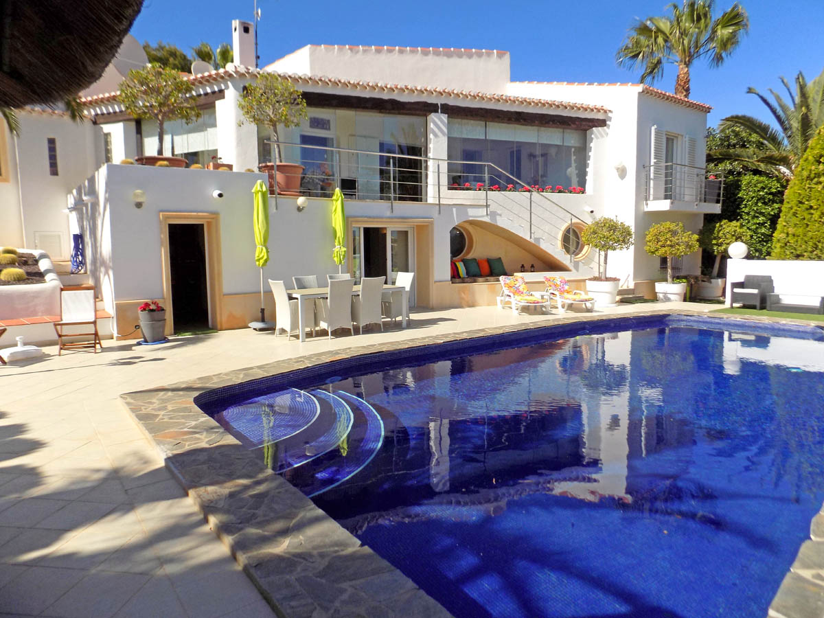 Außenansicht mit 12m x 5,5m Pool, Sonnenterrasse mit Essbereich und integrierter Chill-out-Ecke unter der Treppe zum Obergeschoss.