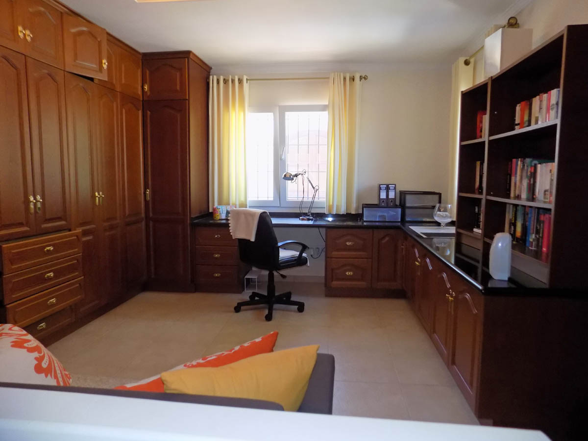 Funktionales Arbeitszimmer mit großen Holz-Einbauschränken, L-förmigem Schreibtisch mit dunkler Arbeitsplatte und integriertem Bücherregal.
