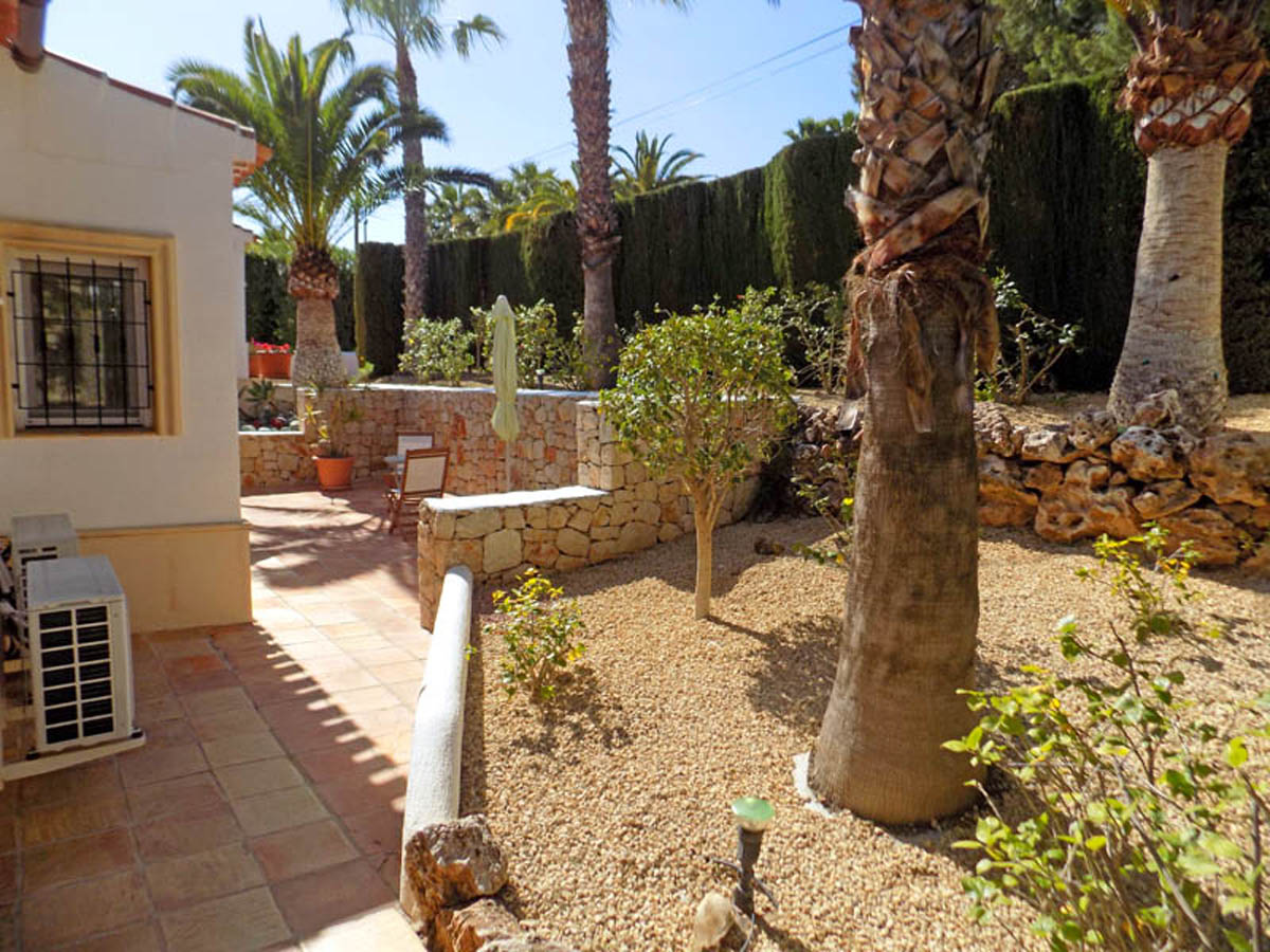 Mediterraner Garten mit Trockensteinmauern, ausgewachsenen Palmen und Terrakottaböden. Die Gestaltung umfasst Kiesbeete und hohe Sichtschutzhecken.