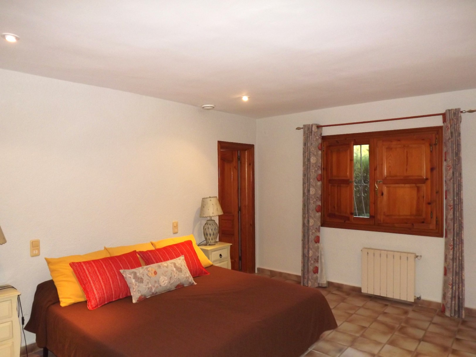 Doppelzimmer mit Terrakotta-Fliesen, traditionellen Holzfensterläden und Zentralheizungskörper. Ausgestattet mit Deckeneinbaustrahlern und Innentüren aus Massivholz.