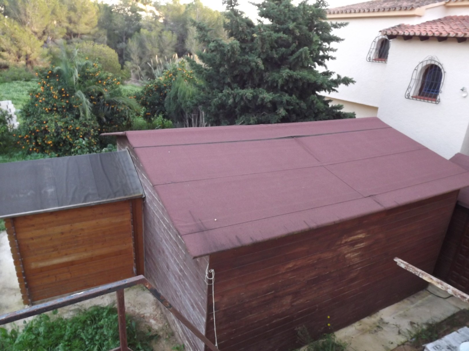Holzschuppen für Lagerzwecke auf dem weitläufigen Grundstück, umgeben von Obstbäumen und typisch mediterraner Bepflanzung.