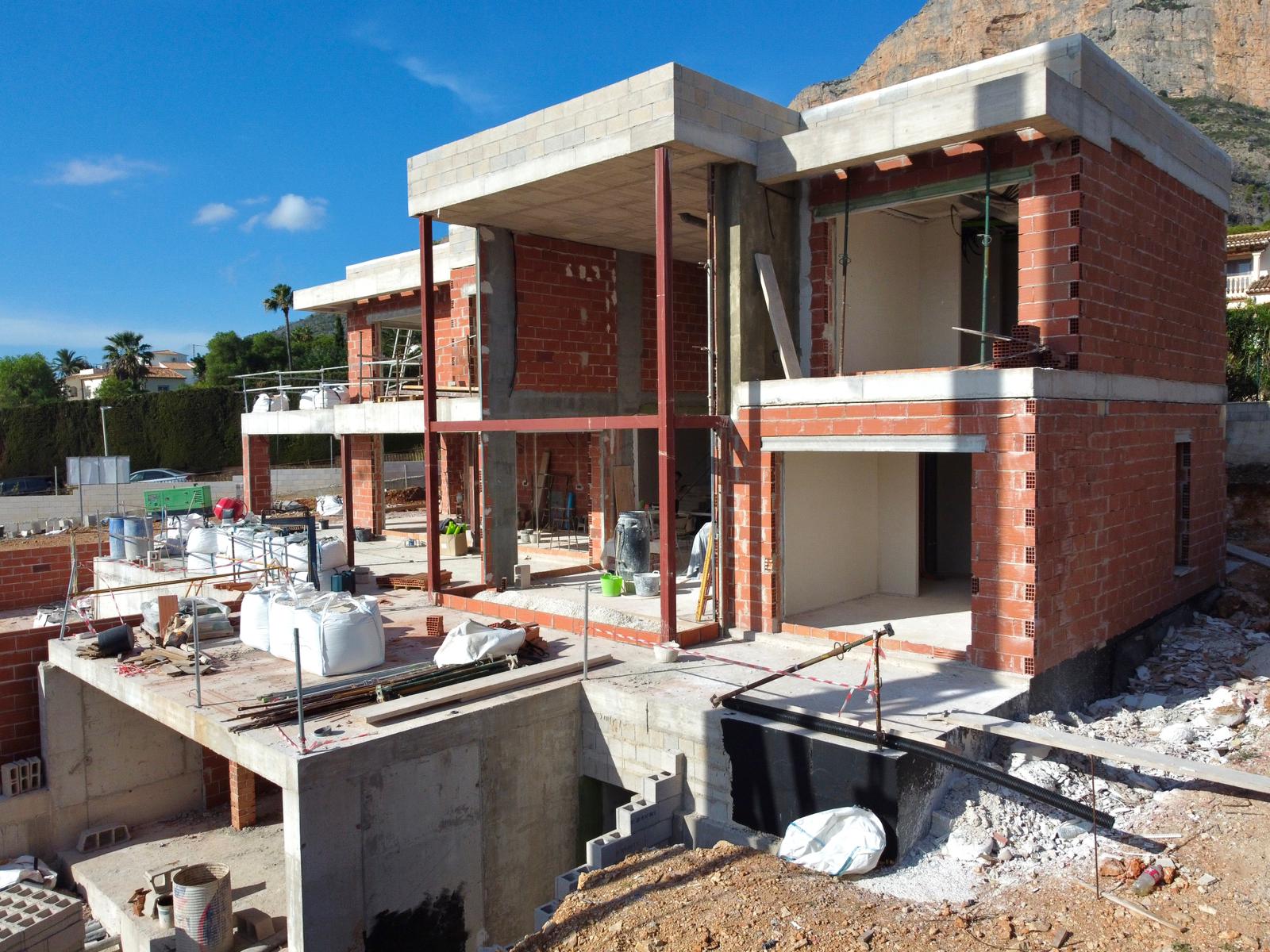 Aktueller Baustatus der Villa mit Ziegelmauerwerk, Betonplatten und Stahlträgern vor der Kulisse des Montgó-Berges in Jávea.