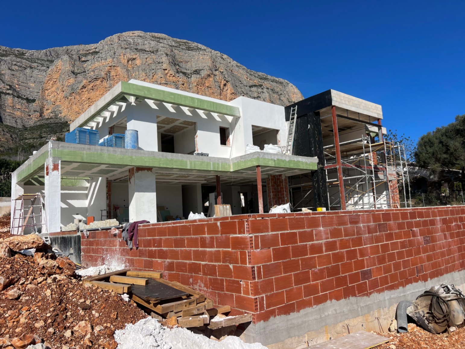 Außenansicht der Villa im Bau vor dem Montgó-Massiv, die zweistöckige Betonstruktur und die großzügig geplanten Terrassenbereiche verdeutlichend.
