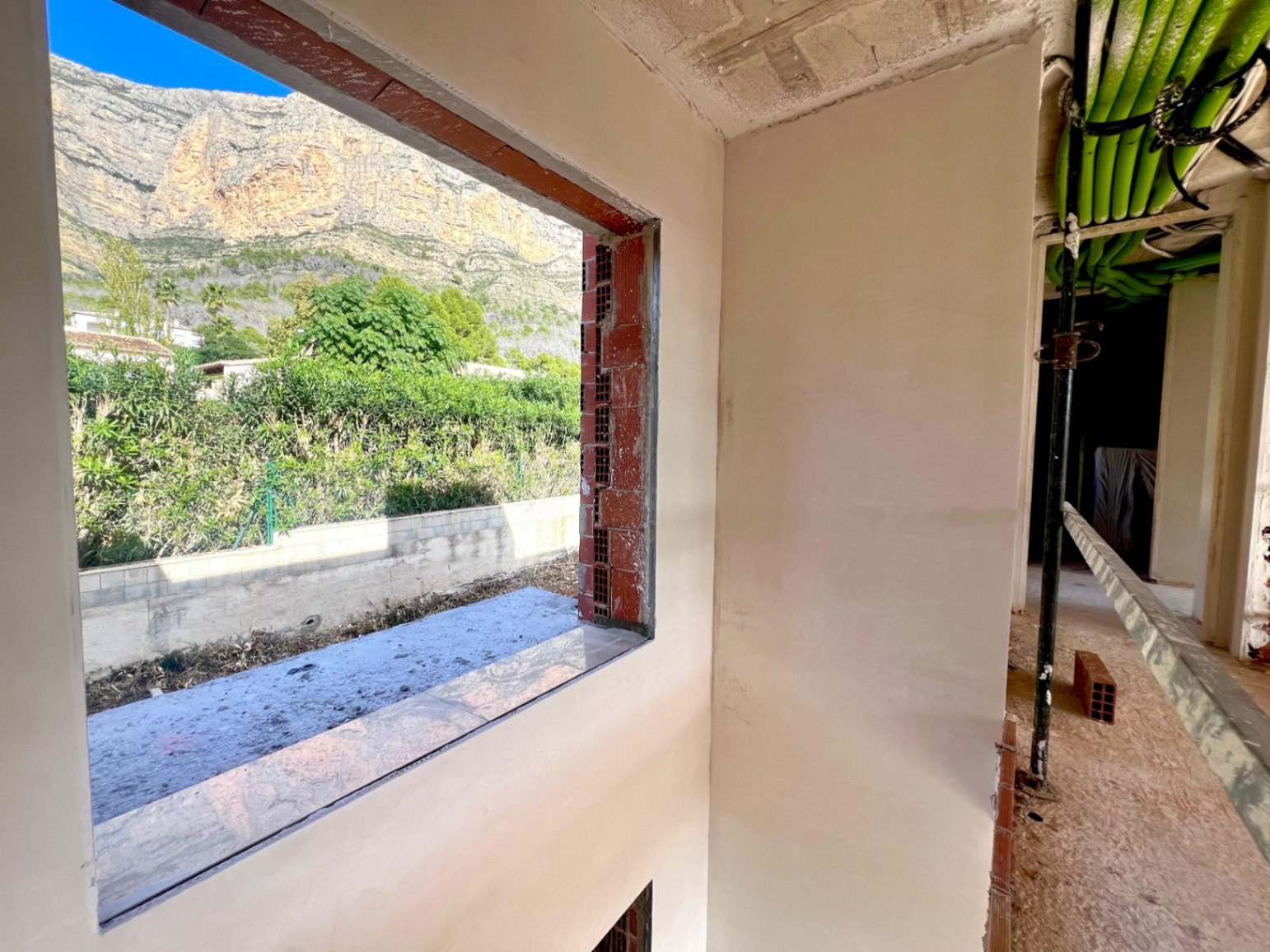 Blick auf den Montgó vom Rohbau aus, der die großzügigen Fensteröffnungen und die installierten Versorgungsleitungen zeigt.