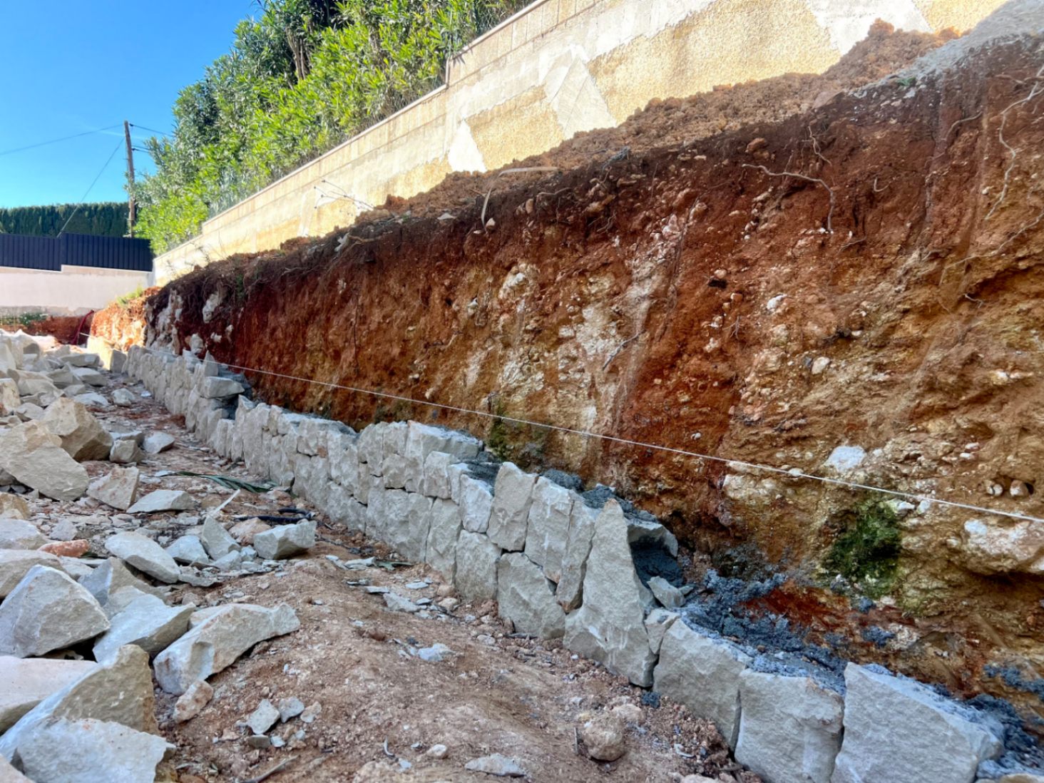 Erste Bauphase mit Errichtung einer Stützmauer aus Naturstein an der ausgehobenen Böschung des Grundstücks in Jávea.