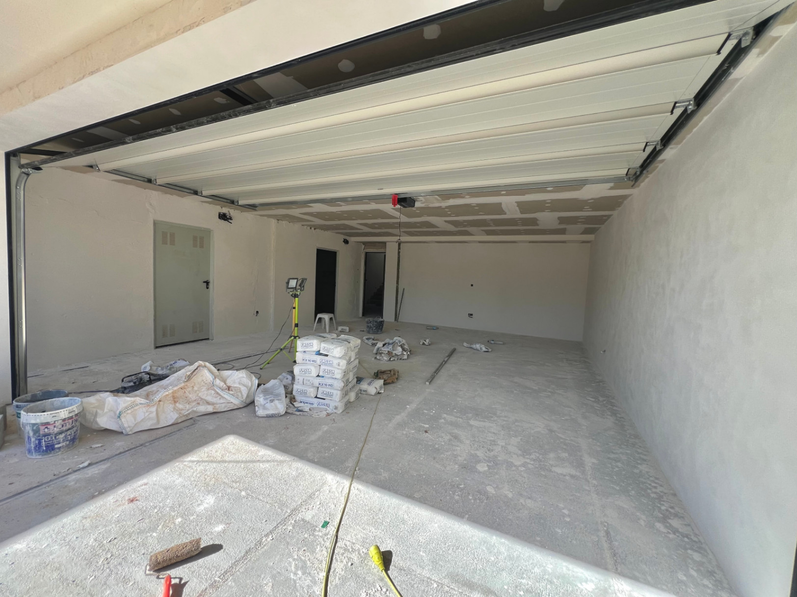 Geräumige Garage im Bau mit weißem Sektionaltor, Betonboden und direktem Zugang zu den Innenräumen der Villa.