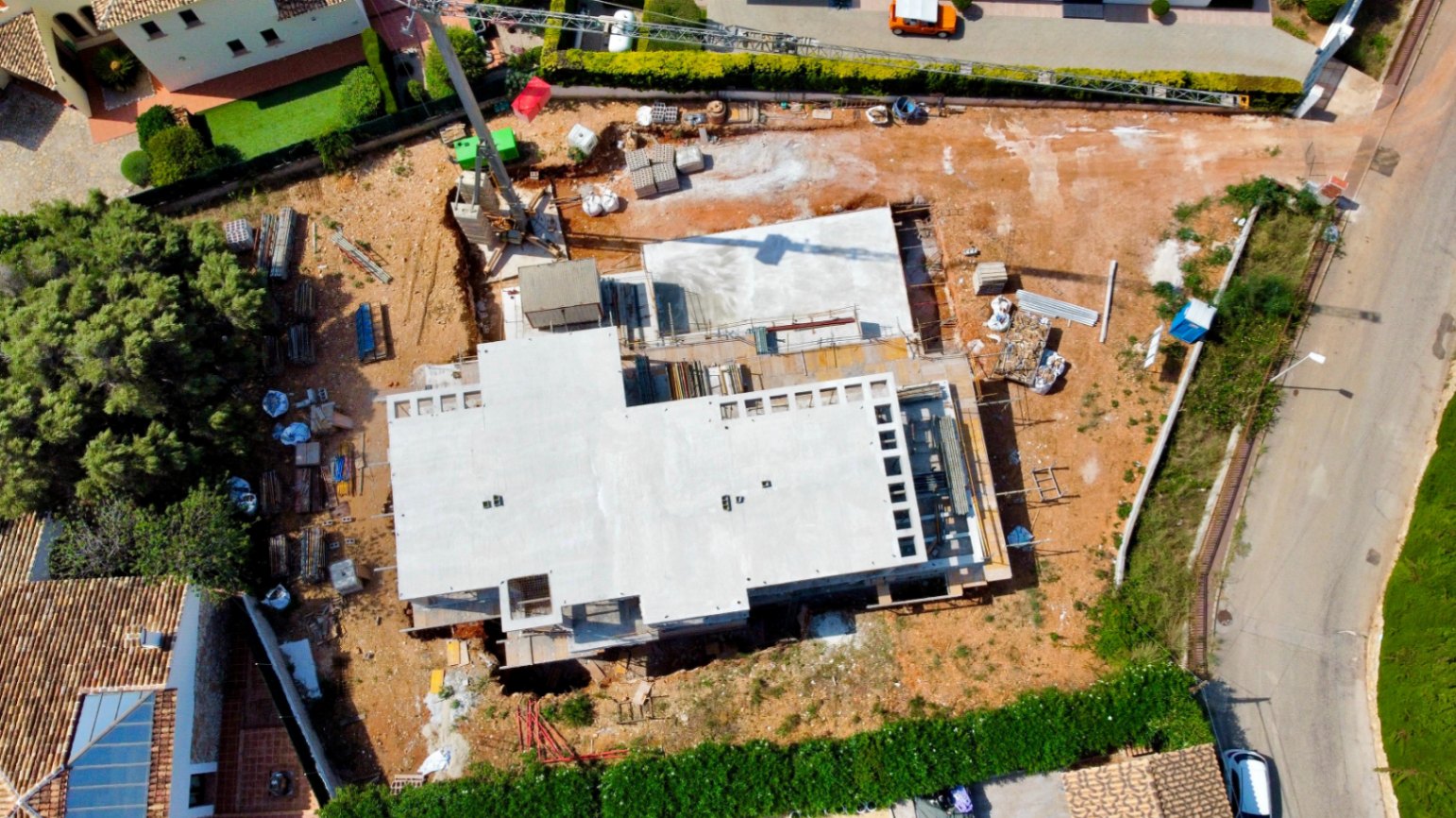 Luftaufnahme des Baufortschritts auf dem flachen Grundstück mit Betonstruktur und Baukran in der Urbanisation El Garroferal del Montgó.