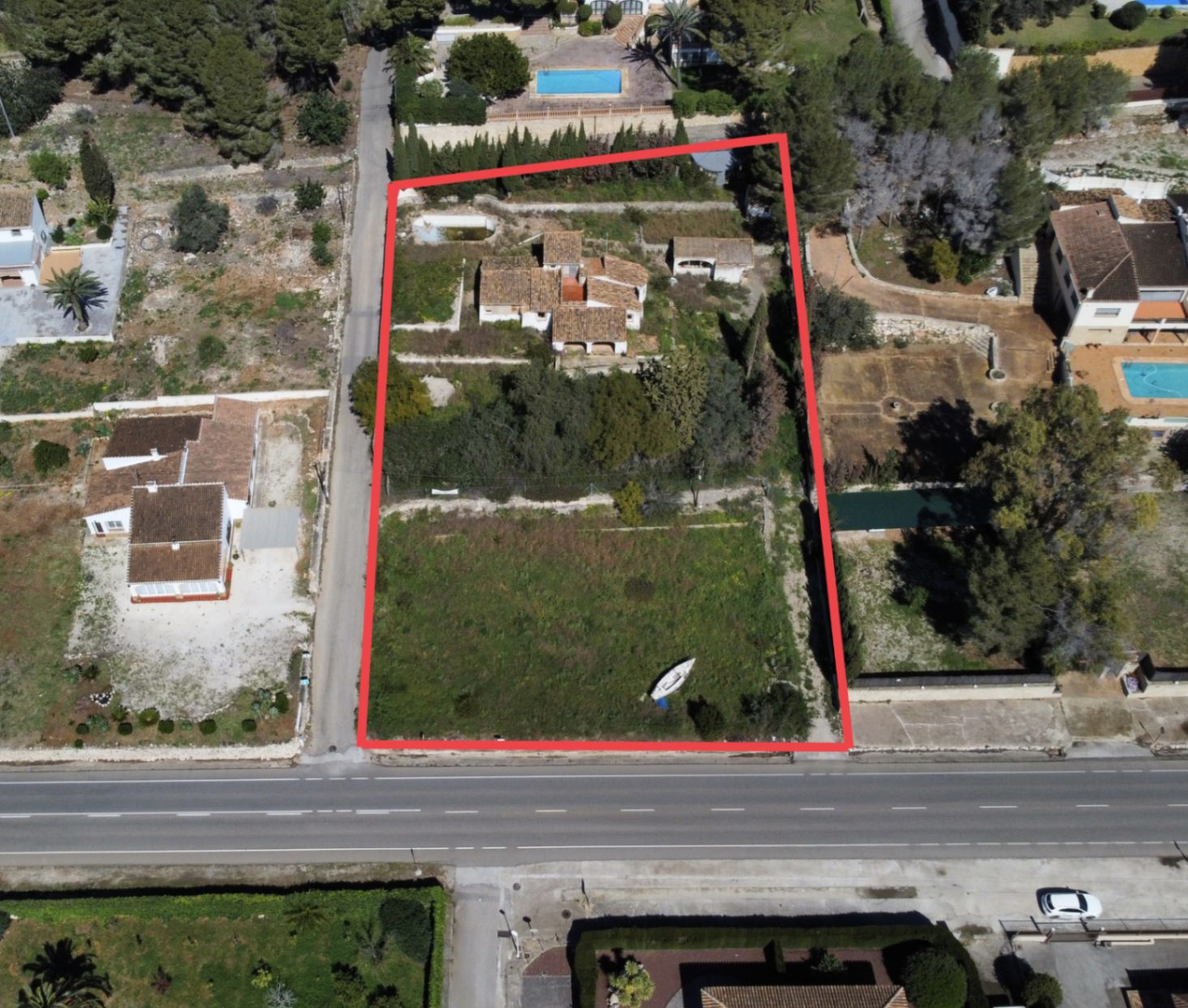 Luftaufnahme des 2.895 m2 großen Grundstücks am Montgó mit rot markierter Grenze, Haupthaus, Nebengebäuden und einer großen Gartenfläche mit direktem Straßenzugang.