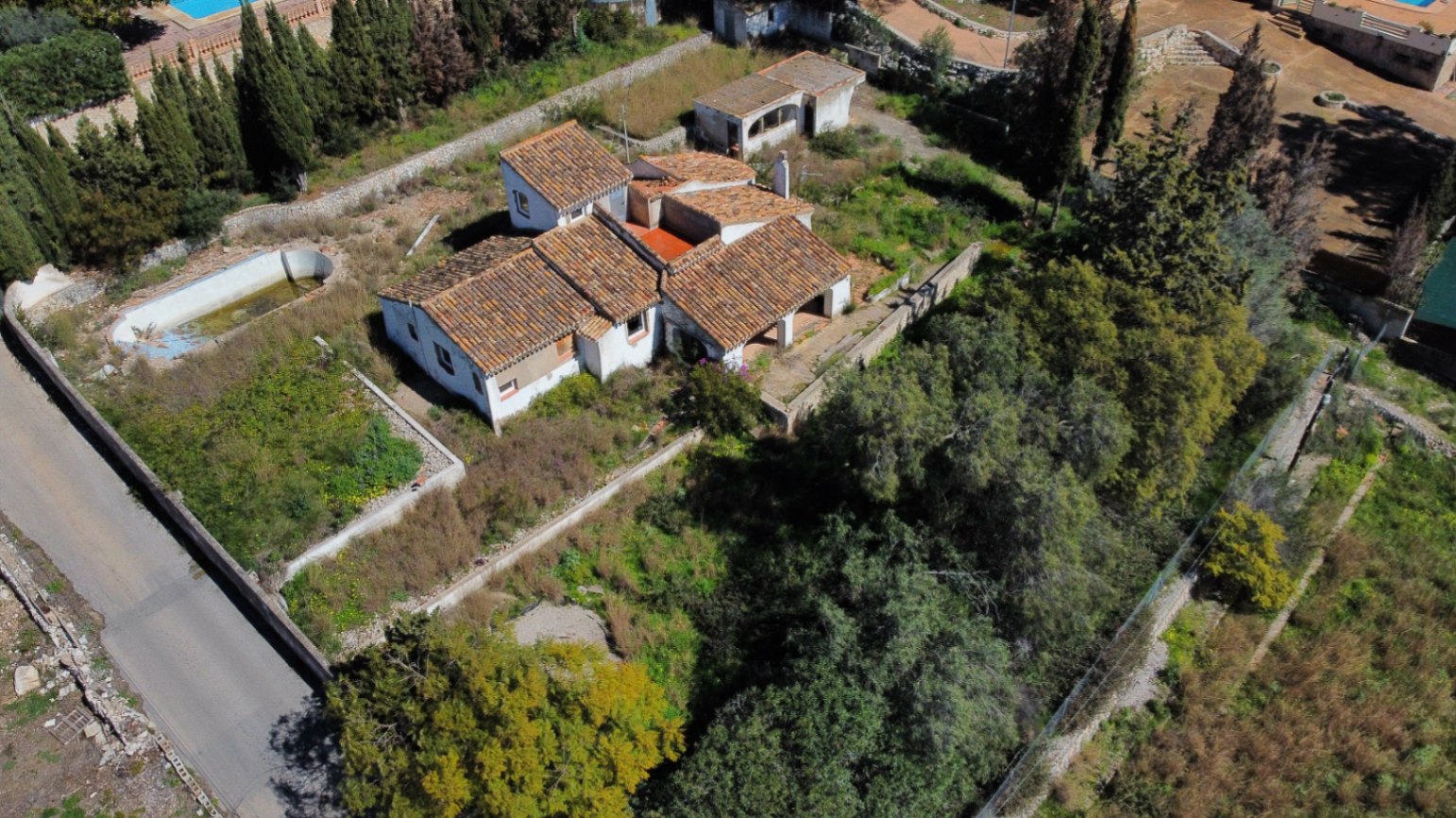 Luftaufnahme des Anwesens mit Terrakotta-Ziegeldächern, dem 2.895 m2 großen Grundstück mit Baumbestand und dem nierenförmigen Pool, der renoviert werden muss.