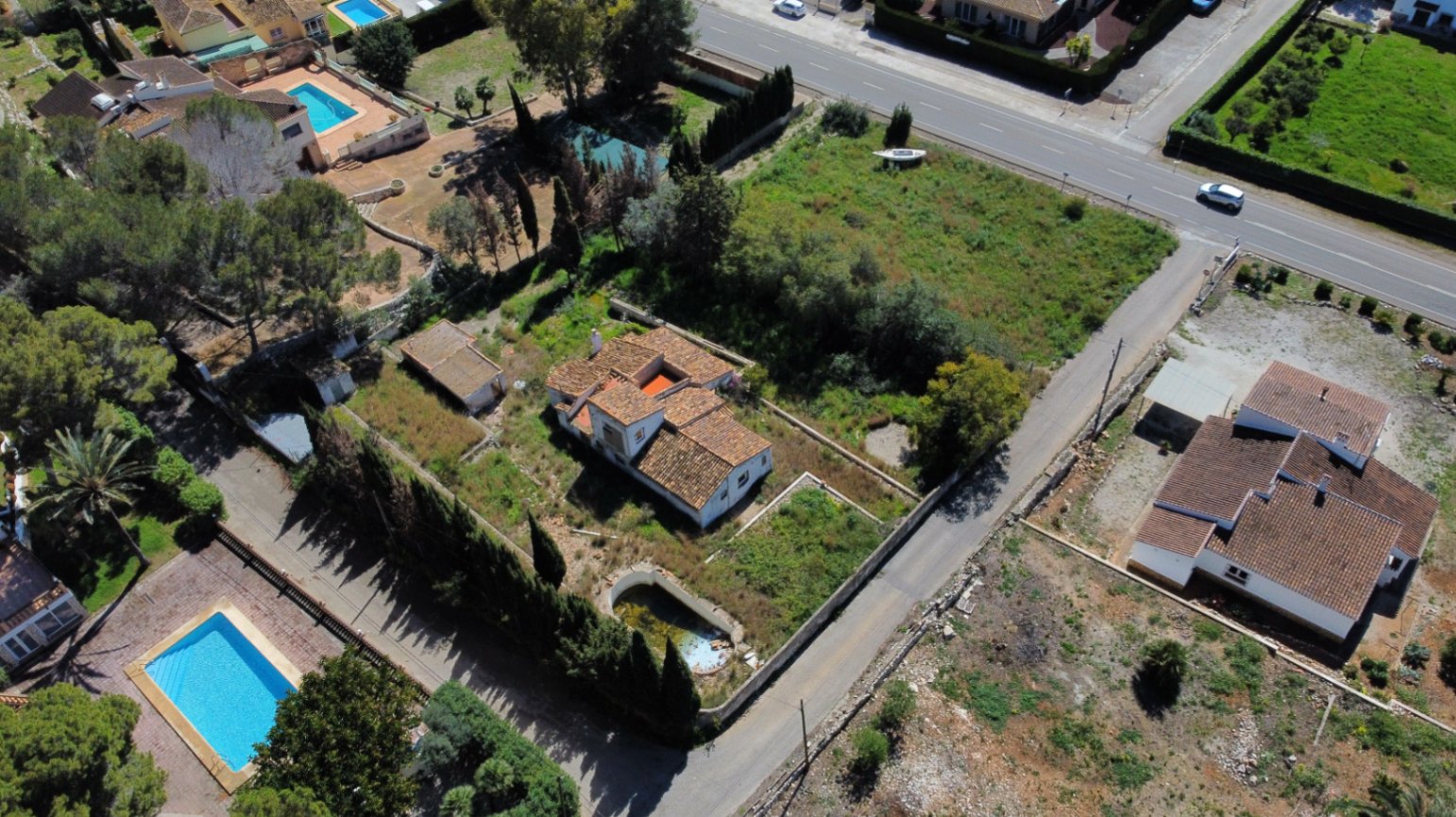 Luftbild des 2.895 m² großen Grundstücks in Jávea; zu sehen sind das Haupthaus mit Ziegeldach, der sanierungsbedürftige Pool und die weitläufige, naturbelassene Gartenfläche.