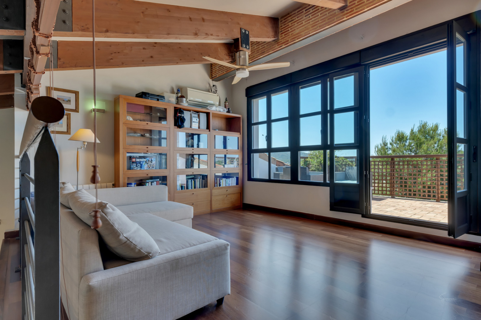 Büro oder Schlafzimmer im Obergeschoss mit Sichtbalkendecke, Parkettboden und großen Fensterfronten, die zu einer privaten Terrasse führen.