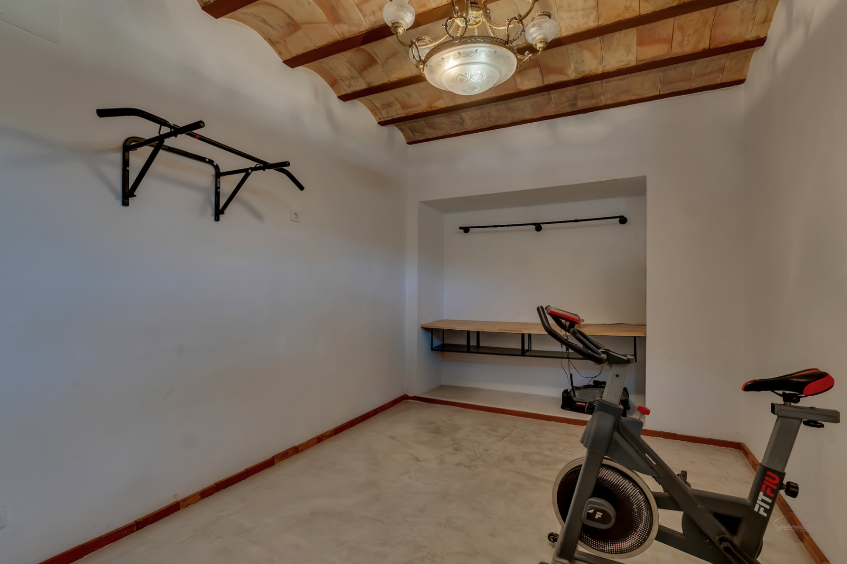 Mehrzweck-Fitnessraum mit traditionellen Gewölbedecken aus Terrakotta, Klimmzugstange, Heimtrainer und einem in die Nische integrierten Schreibtisch.