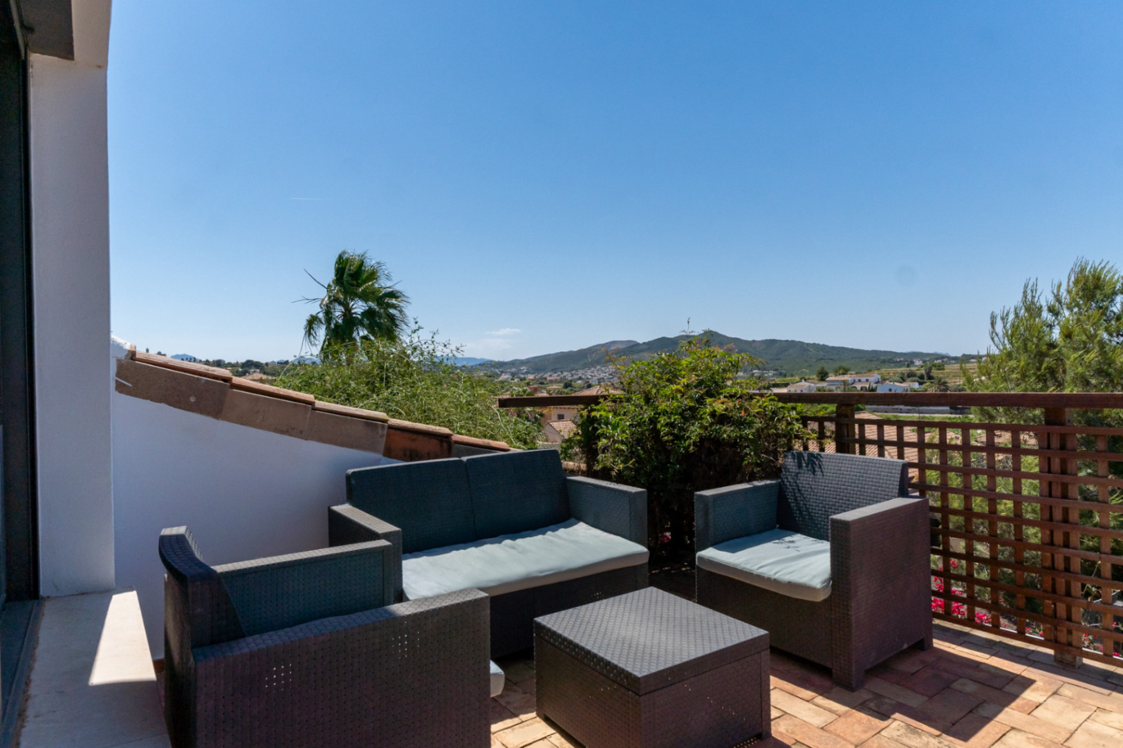 Obere Terrasse mit Lounge-Möbeln aus Polyrattan und Terrakottaboden, die einen weiten Blick über das Tal und die Berge von Jávea bietet.