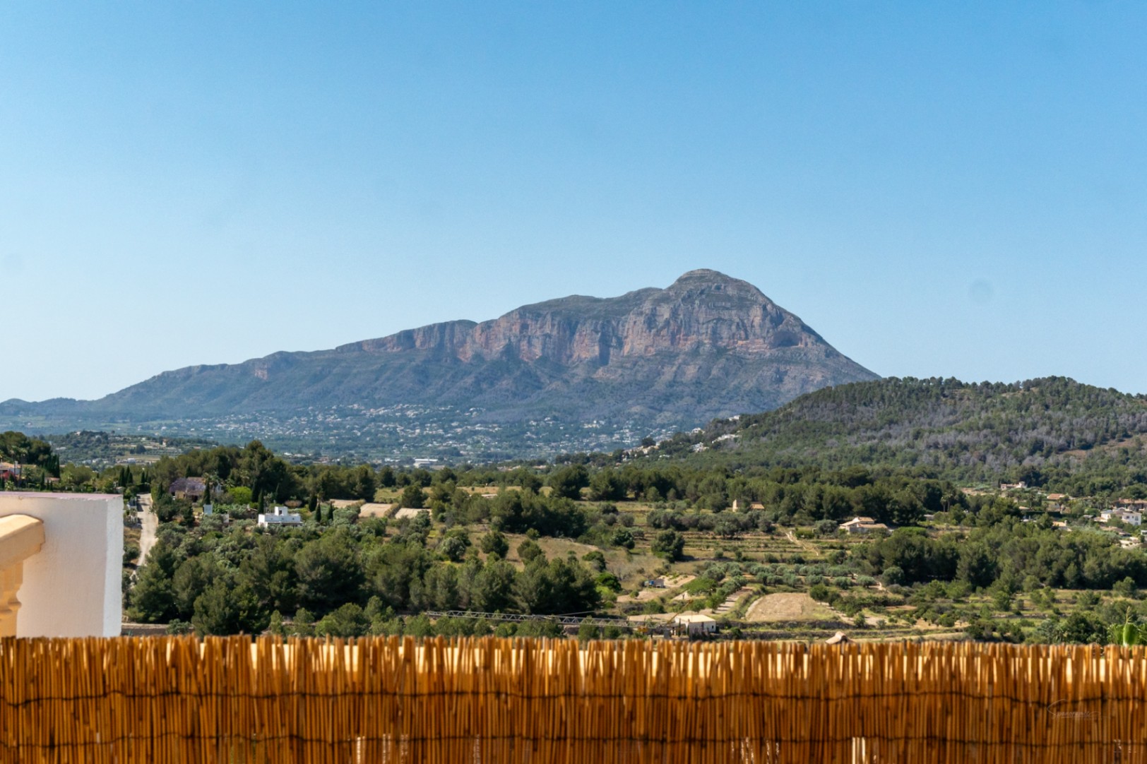 Frontaler Panoramablick auf das Montgó-Massiv von der Terrasse aus, über eine mediterrane Landschaft mit Pinienwäldern und klarem blauem Himmel.