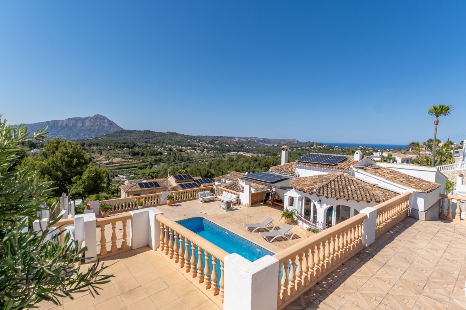 Panoramablick von der oberen Terrasse auf den Pool, die Solaranlage und die weite Aussicht auf den Berg Montgó und das Mittelmeer.