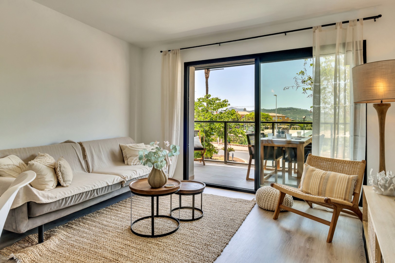Heller Wohnbereich mit Möbeln in neutralen Tönen, Holzboden und direktem Zugang zu einer privaten Terrasse mit Essbereich im Freien und freier Aussicht.