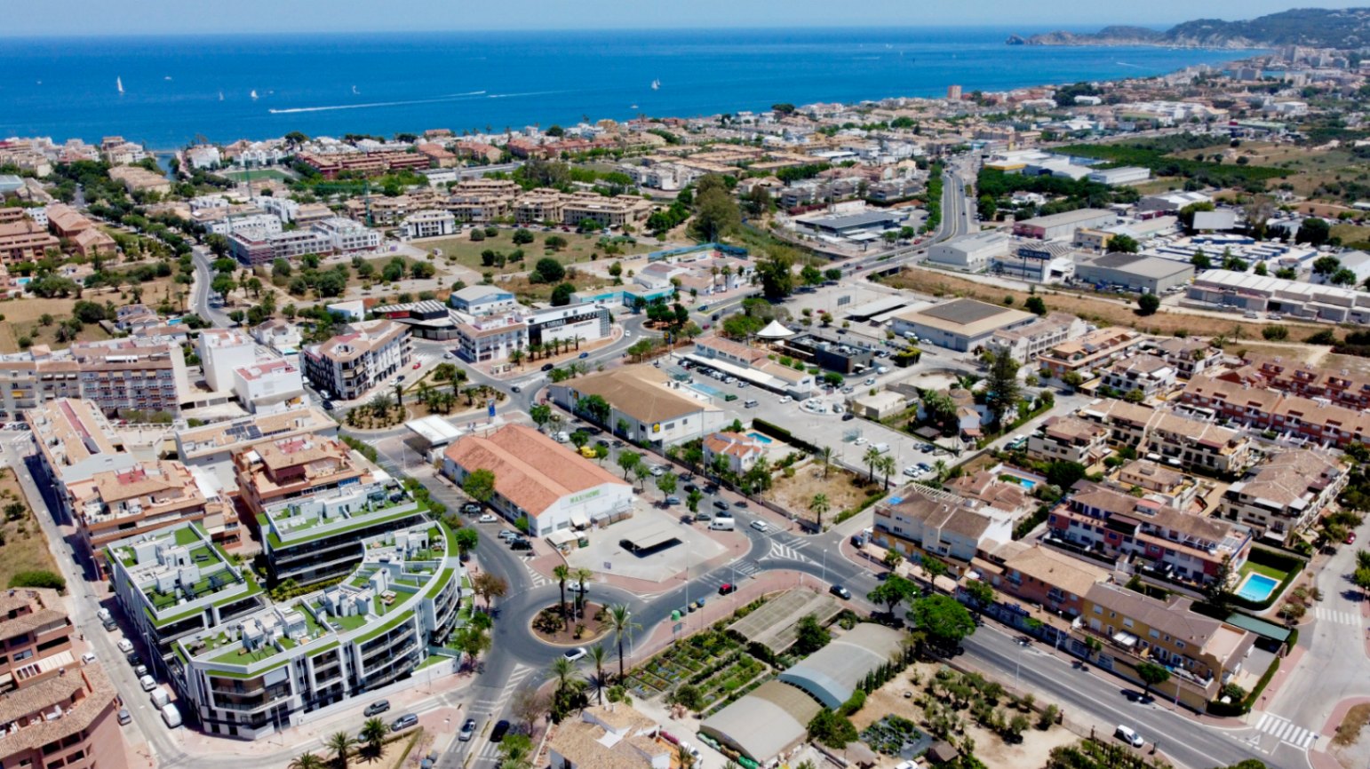 Luftaufnahme des modernen Wohngebäudes mit begrünten Dachterrassen in zentraler Lage zwischen der Altstadt und dem Hafen von Jávea mit Blick auf die Küste.