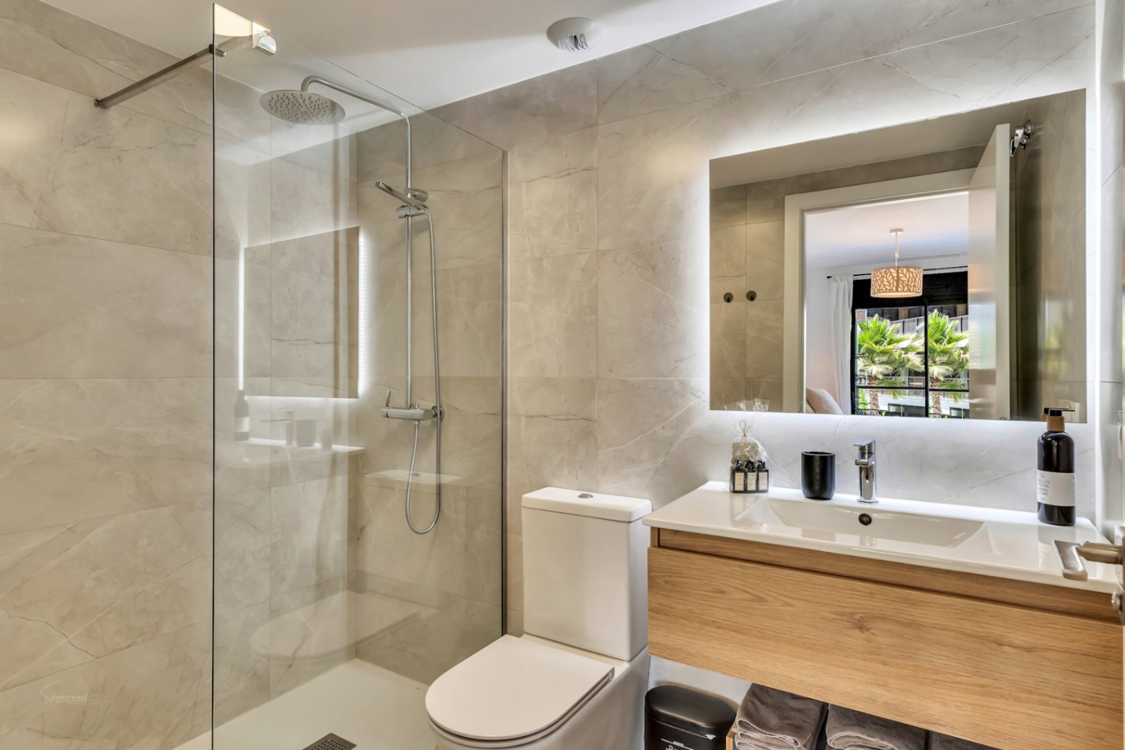 Modernes Badezimmer mit Regendusche, Glastrennwand und großformatigen Fliesen. Ausgestattet mit einem schwebenden Holzwaschtisch und einem eleganten LED-hinterleuchteten Spiegel.