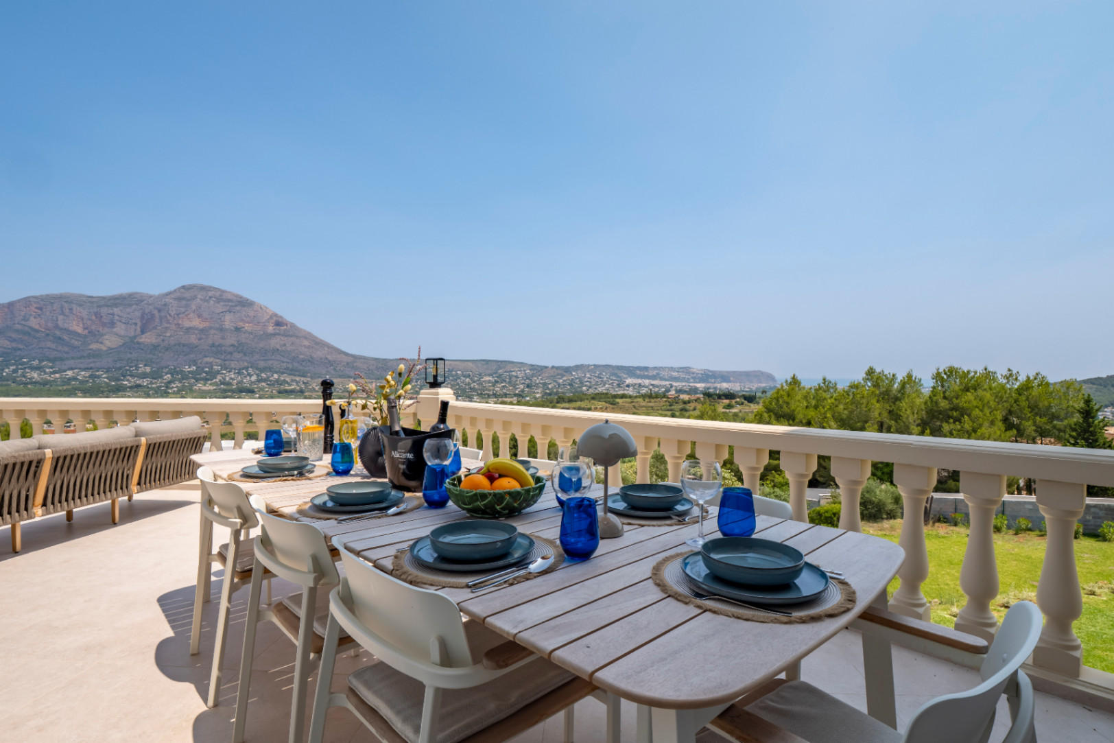 Essbereich im Freien mit Holztisch und Panoramablick auf die Berge und die Küste von der Terrasse.