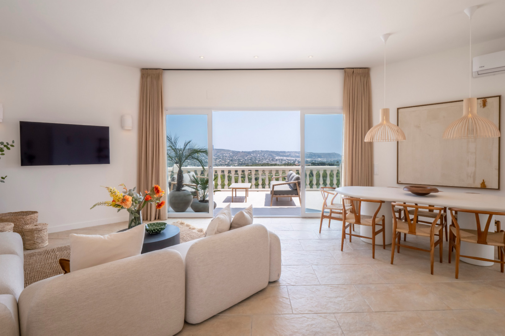 Heller Wohn-Essbereich mit Zugang zur Terrasse und Panoramablick. Modernes Design mit hellen Möbeln und natürlichen Akzenten.