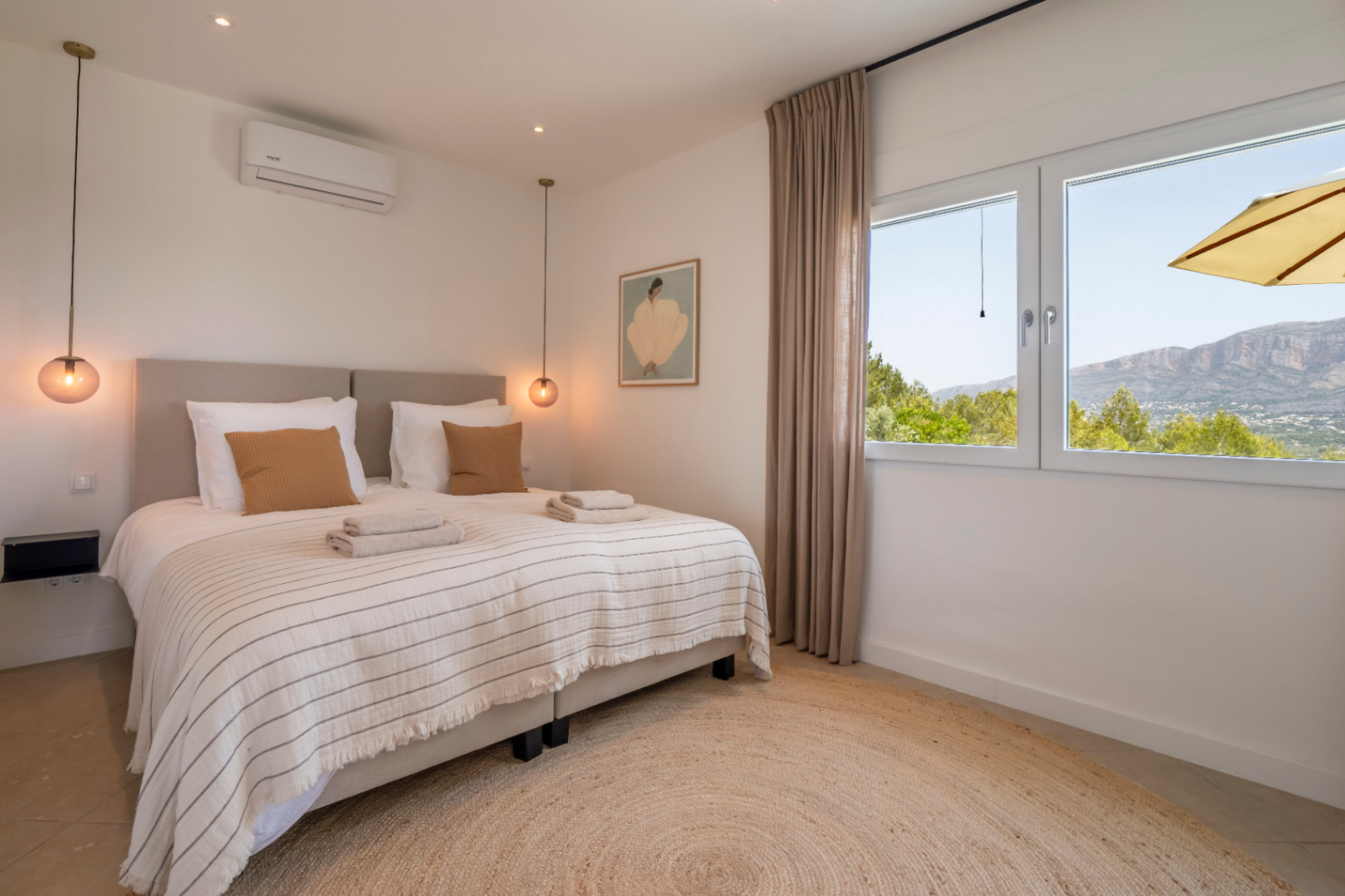 Helles Schlafzimmer mit rundem Jute-Teppich und Bergblick.