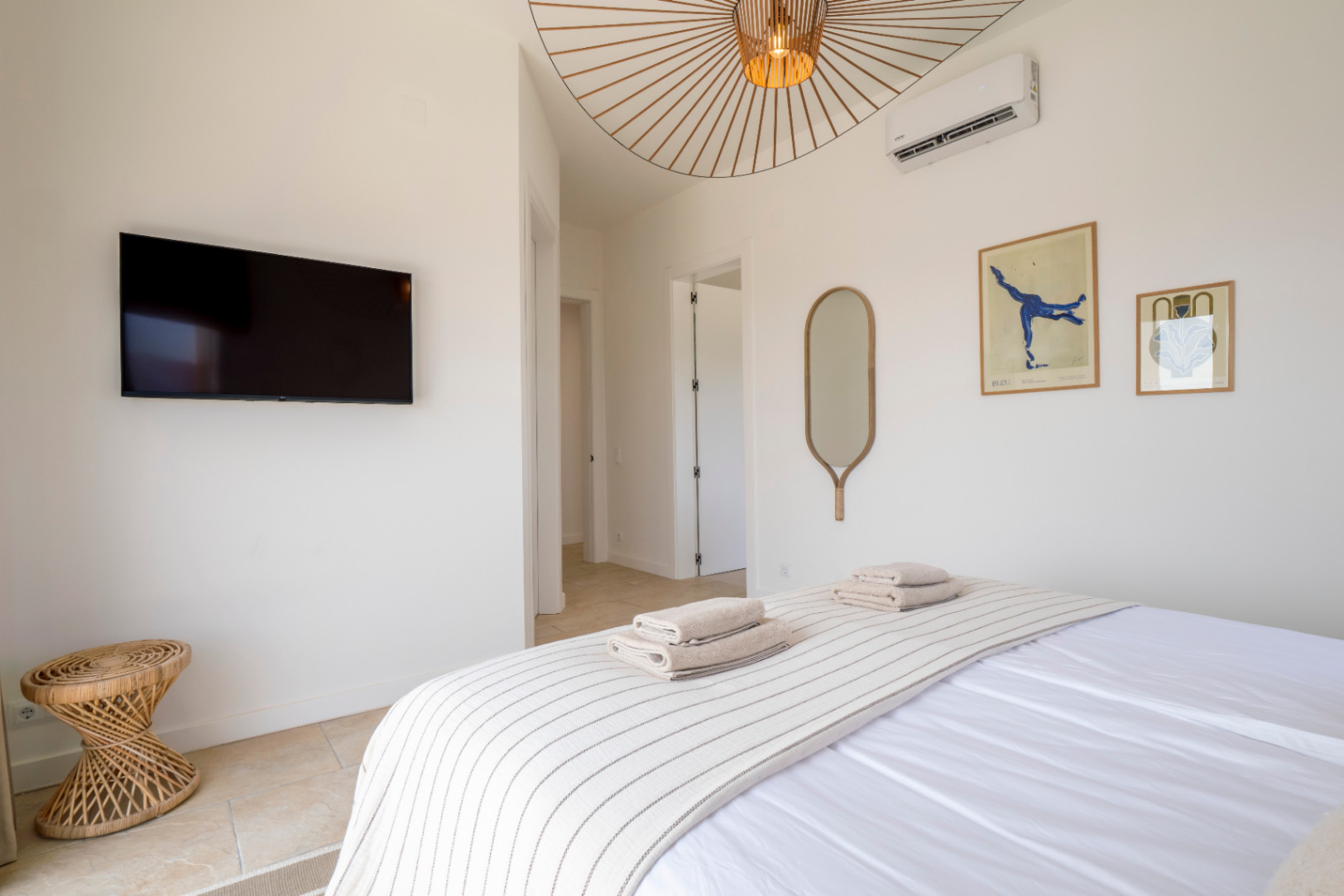 Helles Schlafzimmer mit TV, dekorativem Spiegel und Design-Deckenleuchte.