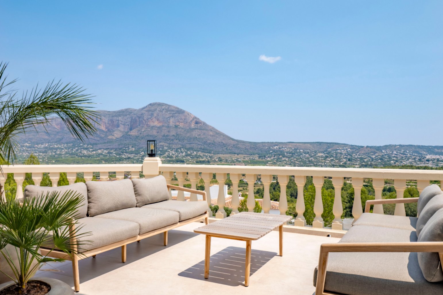 Terrasse mit klassischer Balustrade, Gartenmöbeln aus Holz und Panoramablick auf die Berge.