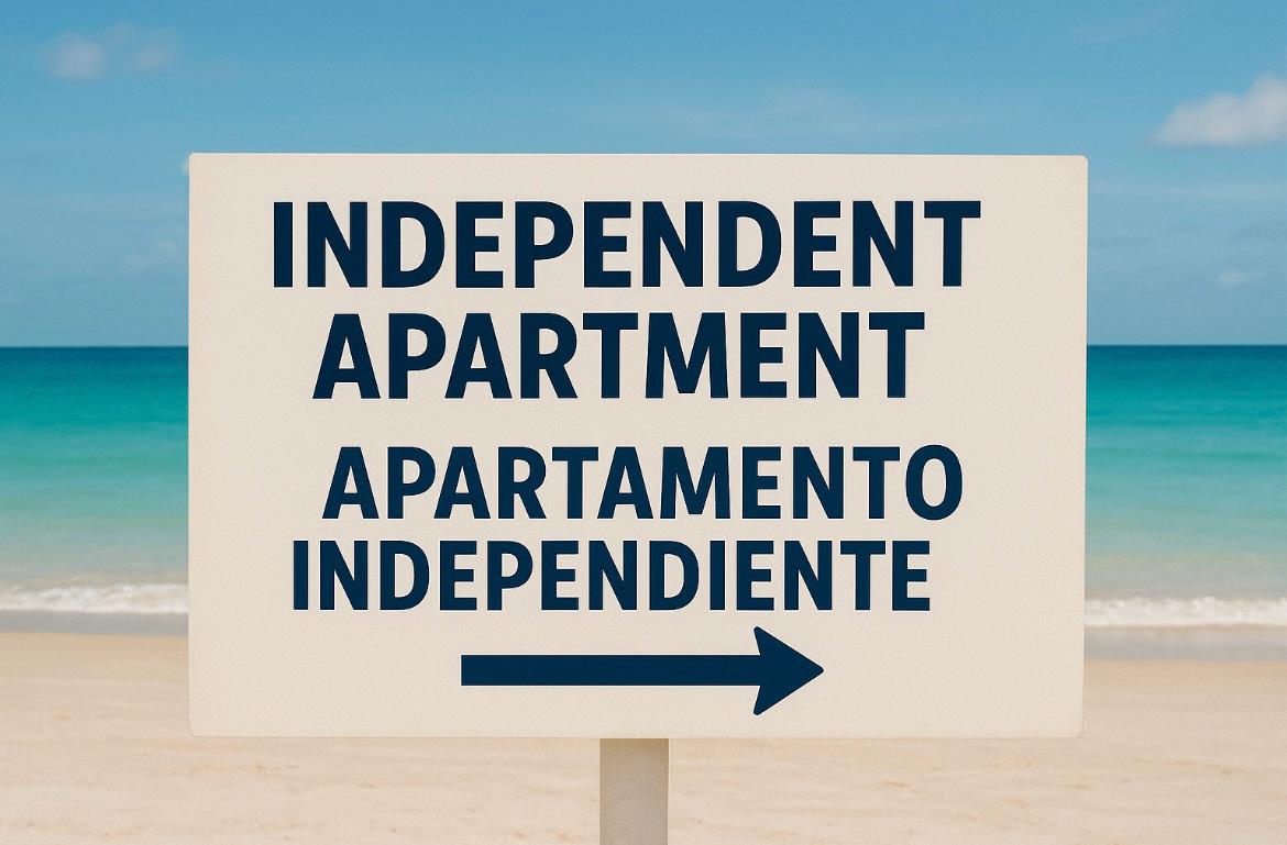Zweisprachiges Schild am Strand, das die Richtung zu unabhängigen Apartments anzeigt.
