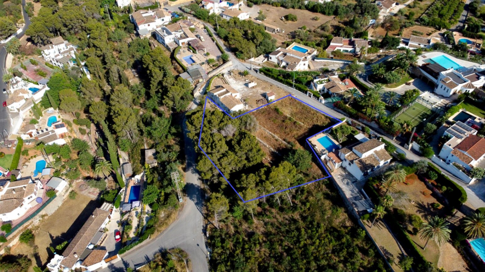 Luftaufnahme des 1.908 m² großen Grundstücks mit markierten Grenzen, Pinienbestand und Einbettung in ein gewachsenes Wohngebiet.