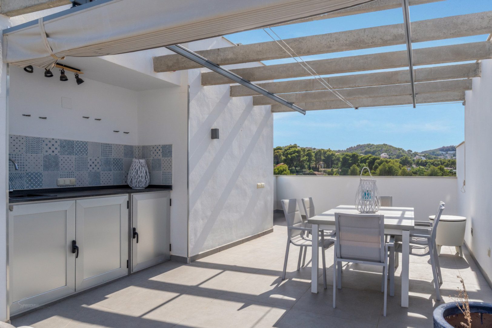 Private Dachterrasse mit Außenküche, Essbereich und Pergola mit ausfahrbarer Markise, die einen weiten Blick auf die umliegende Hügellandschaft bietet.